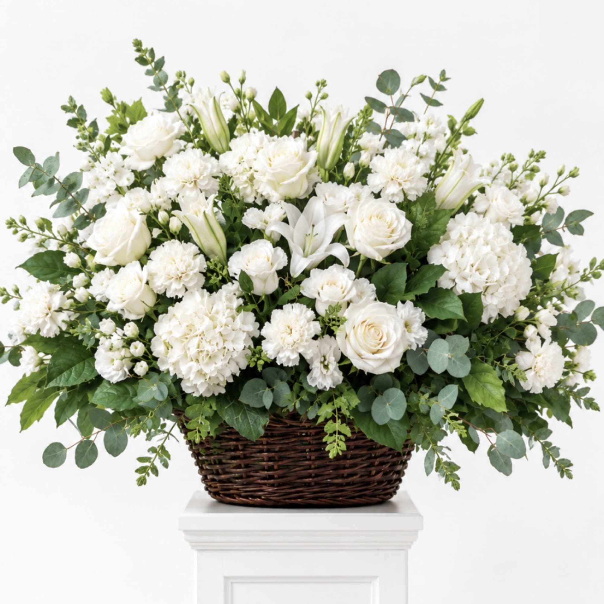 White floral arrangement in a wicker basket with eucalyptus accents