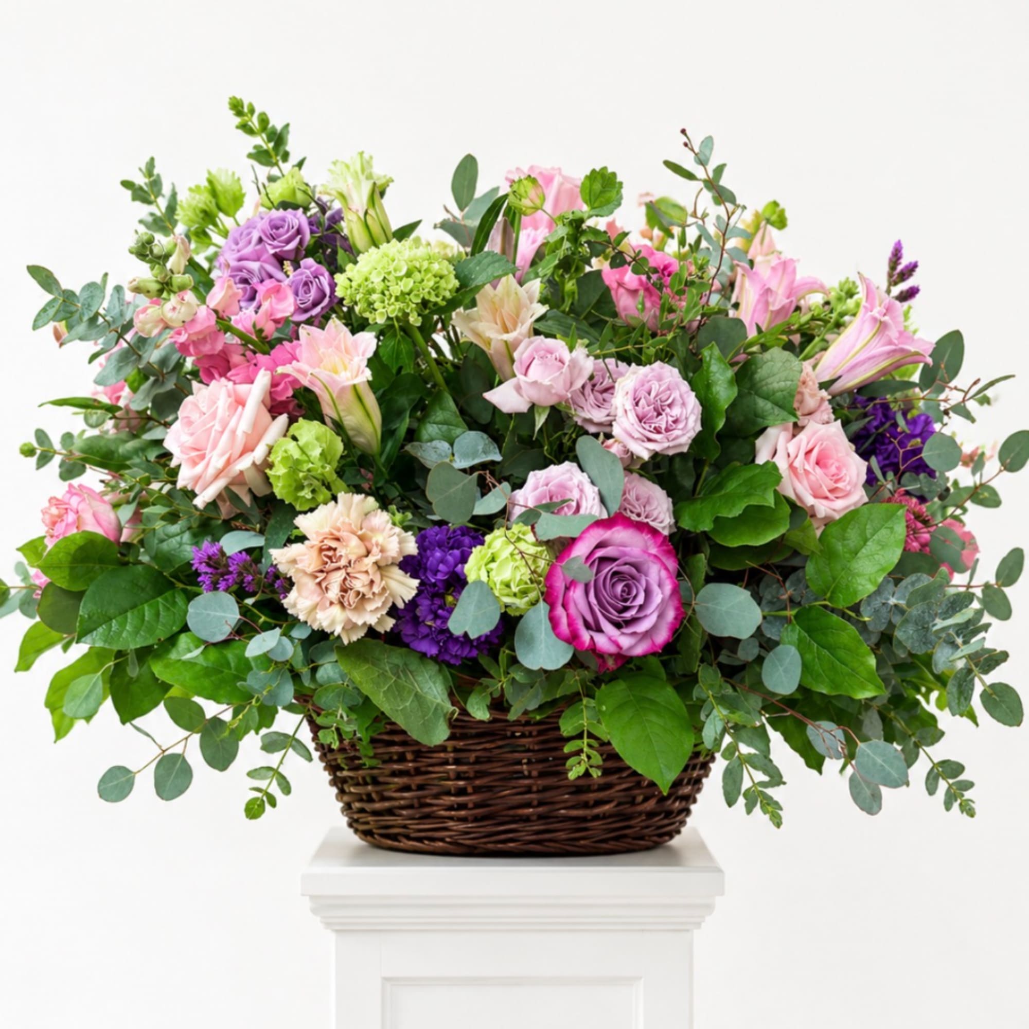 Mixed pink, purple, and green floral arrangement in a wicker basket