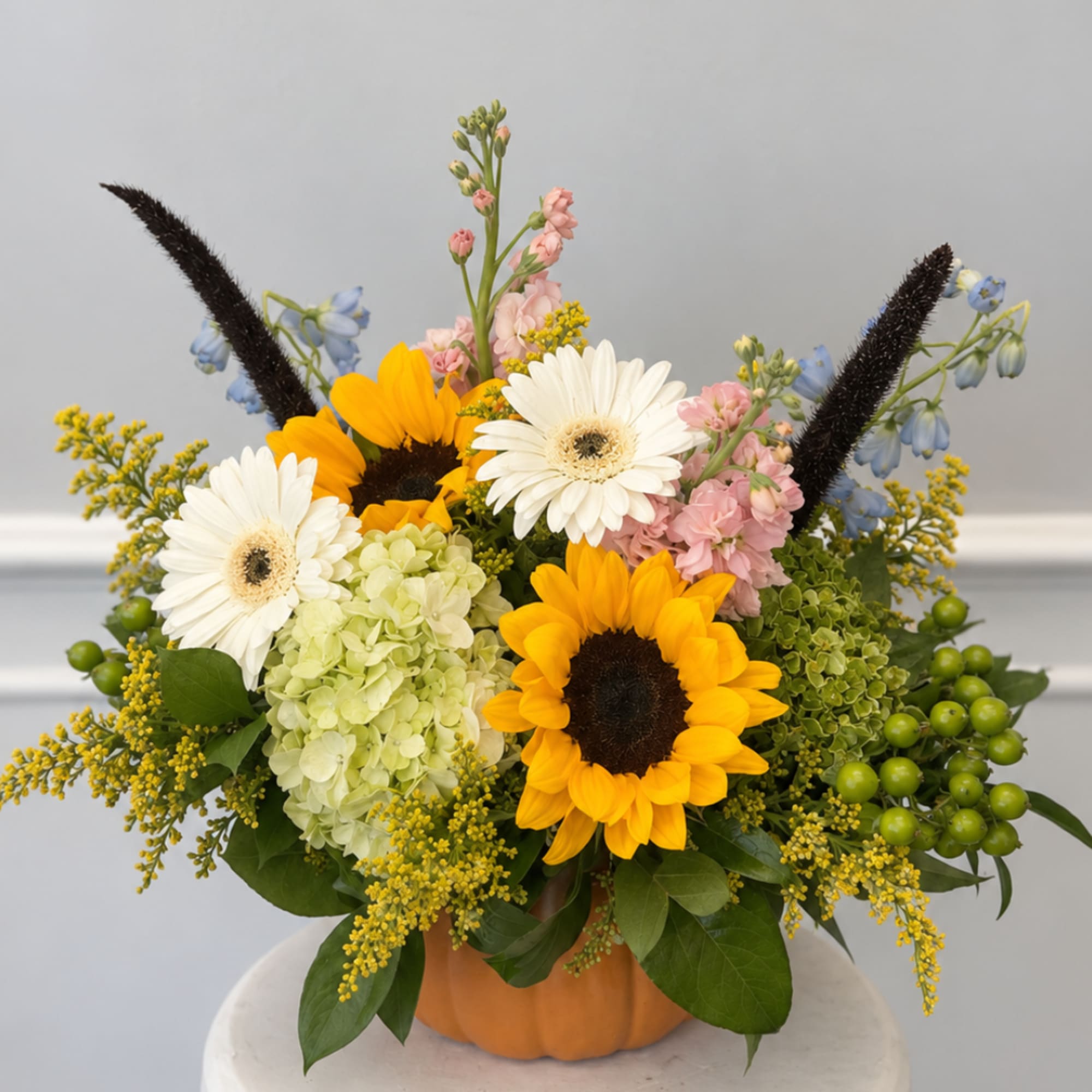 Sunflower and daisy arrangement in a pumpkin-shaped container