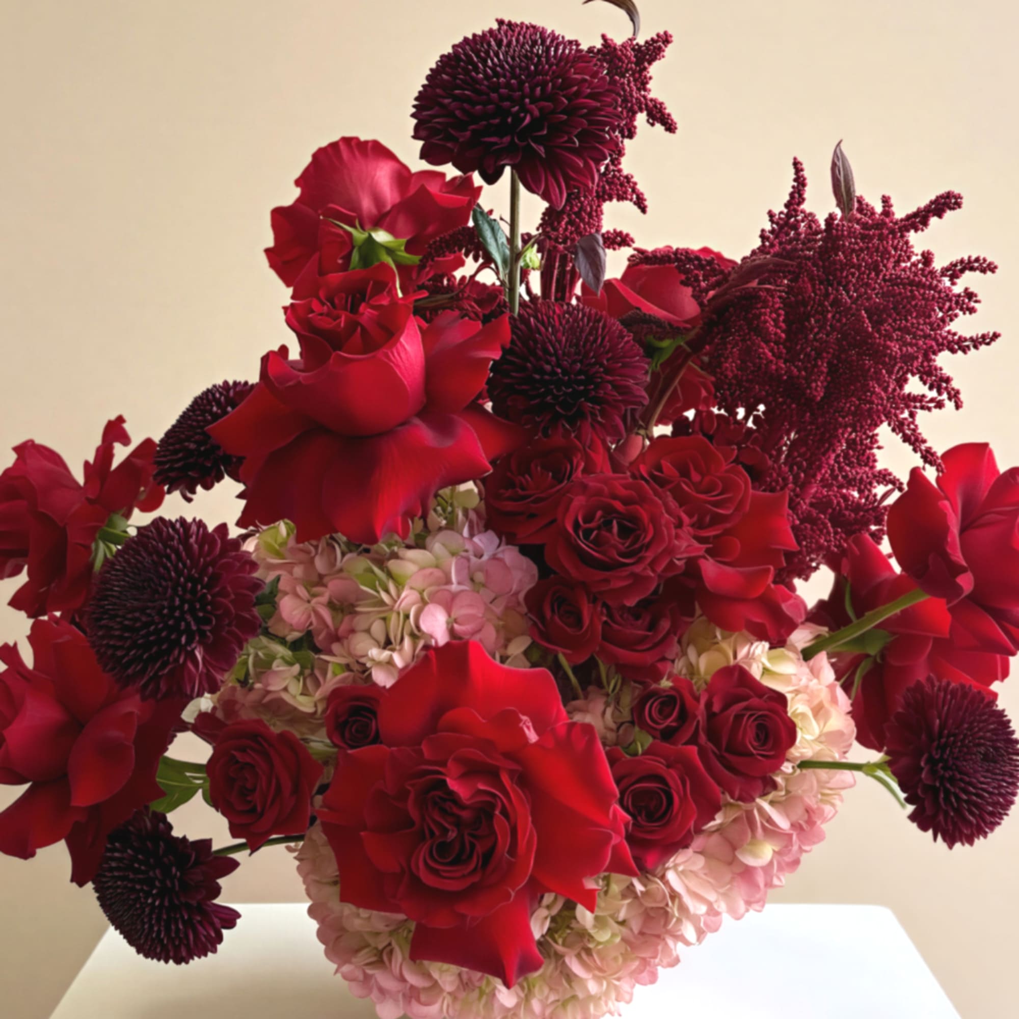 Red roses and dark burgundy blooms arranged with pale pink hydrangeas