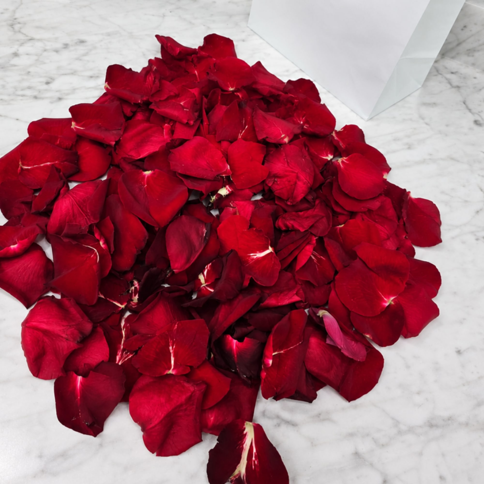 Pile of red rose petals on a marble surface