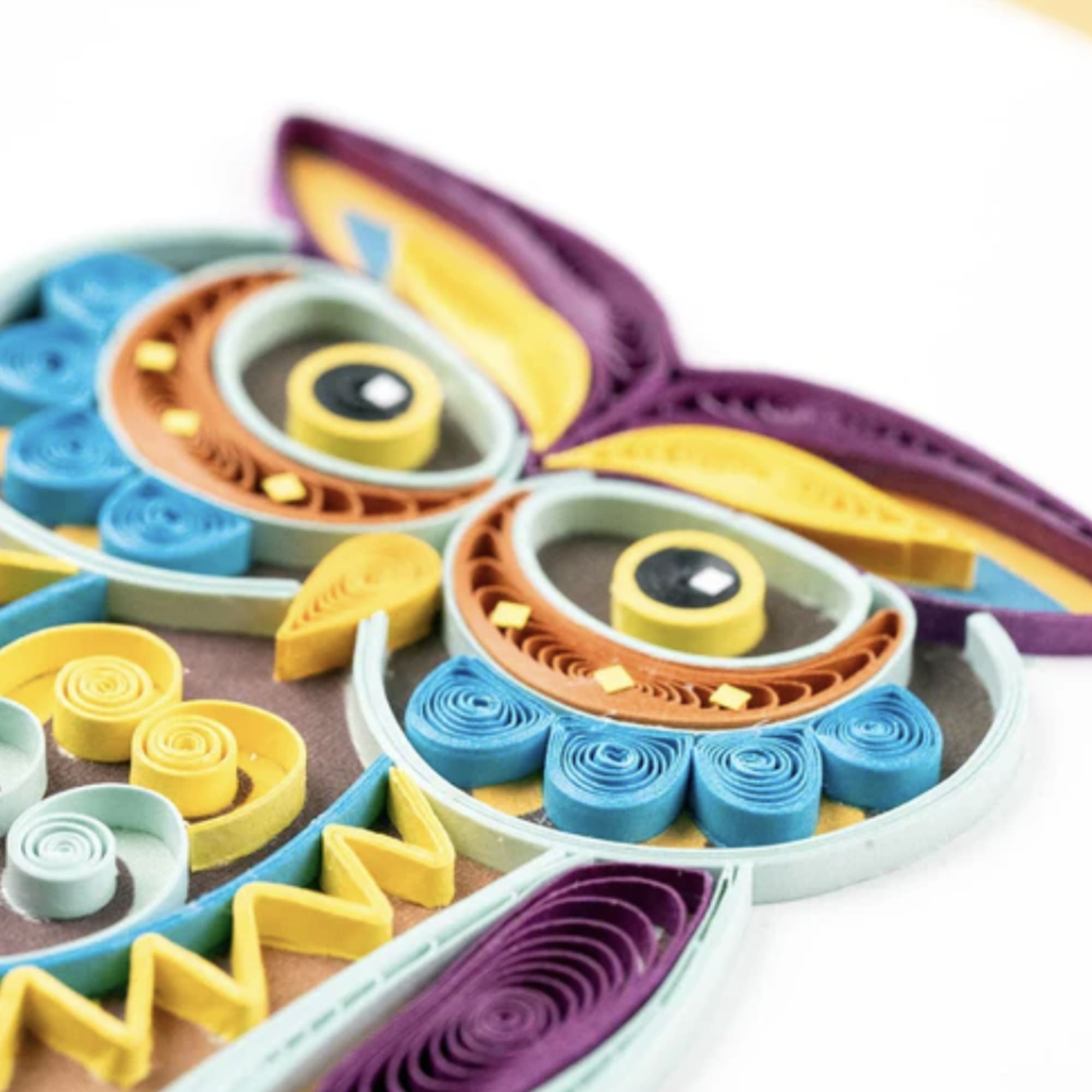 Colorful quilled paper owl decoration on a white background