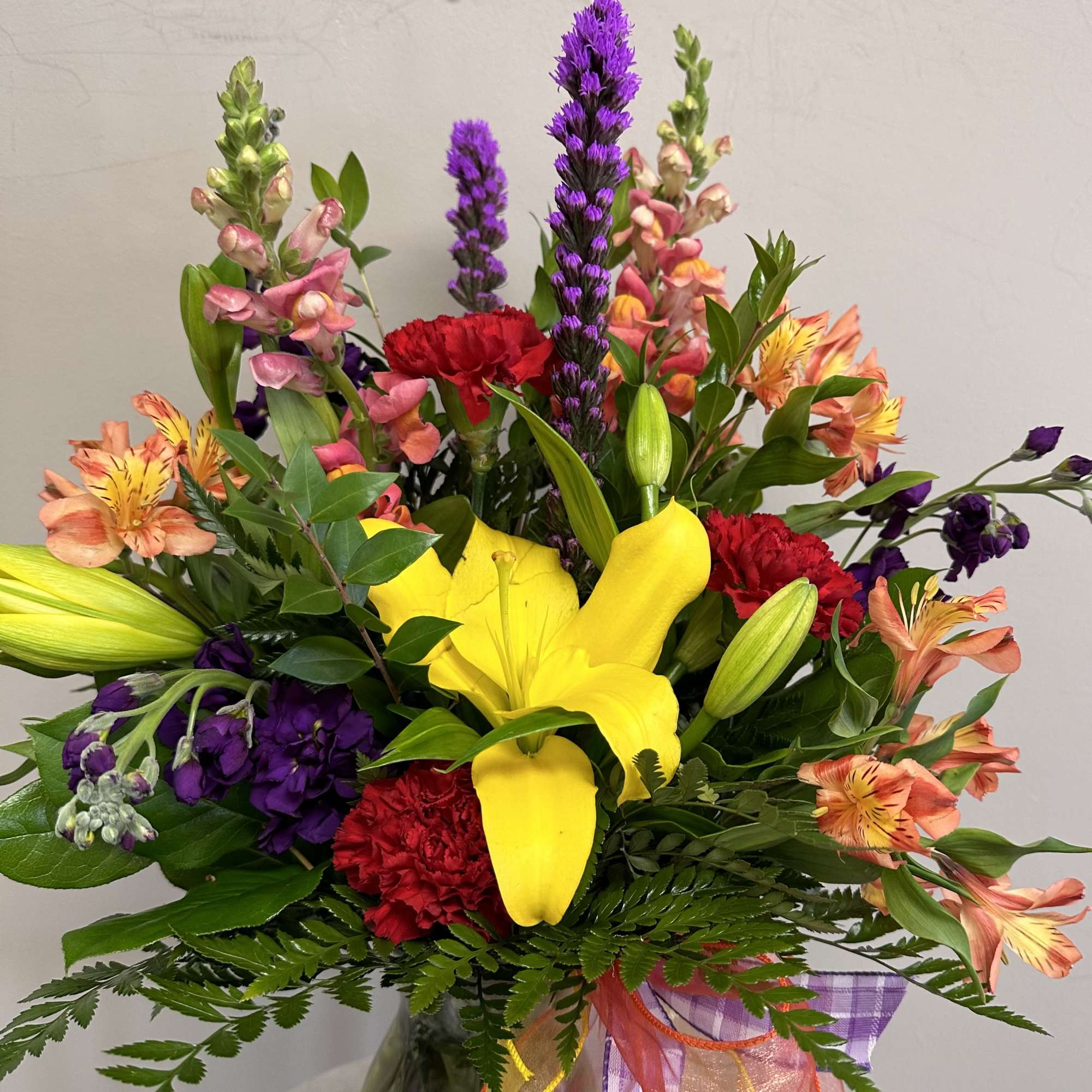 Colorful bouquet with yellow lilies, red carnations, and purple spikes