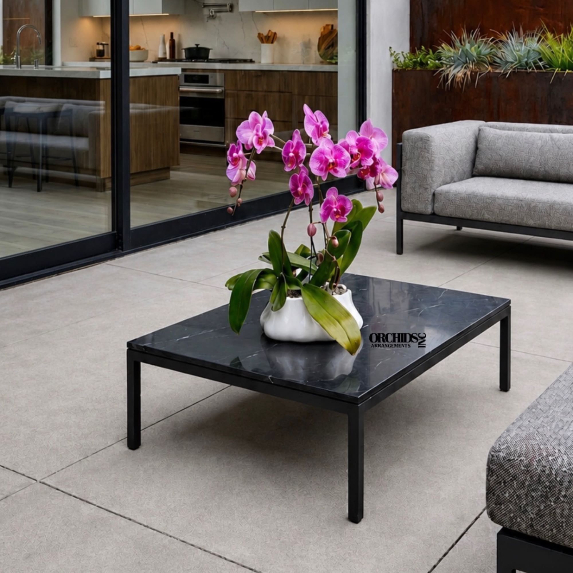 Pink orchid plant in a white ceramic pot on a black table