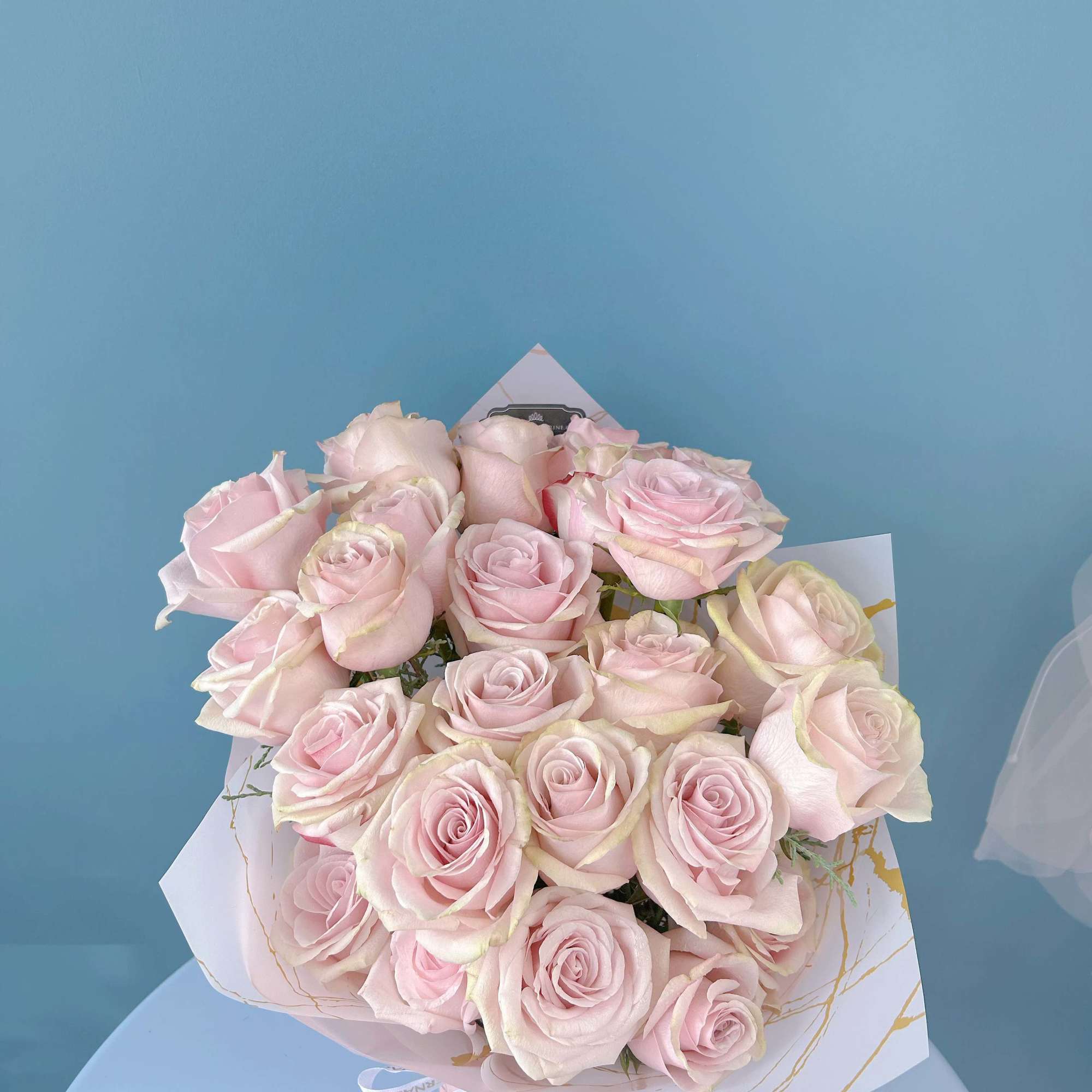 Bouquet of pale pink roses wrapped in white paper