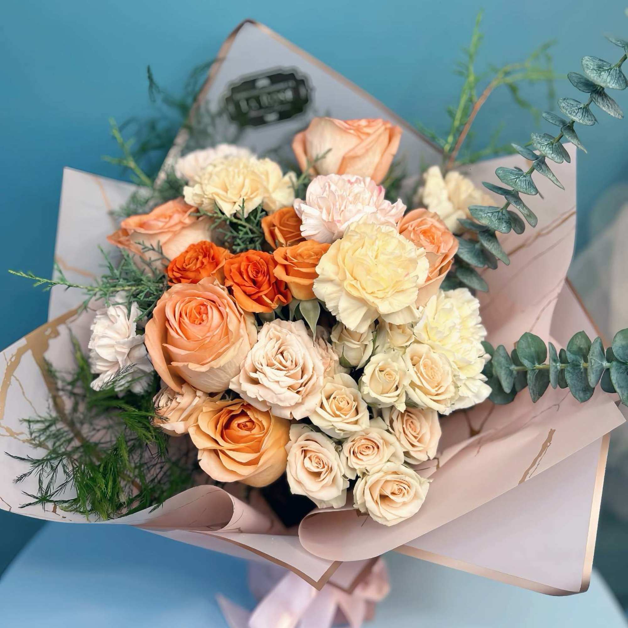 Bouquet of peach and cream roses wrapped in pale paper