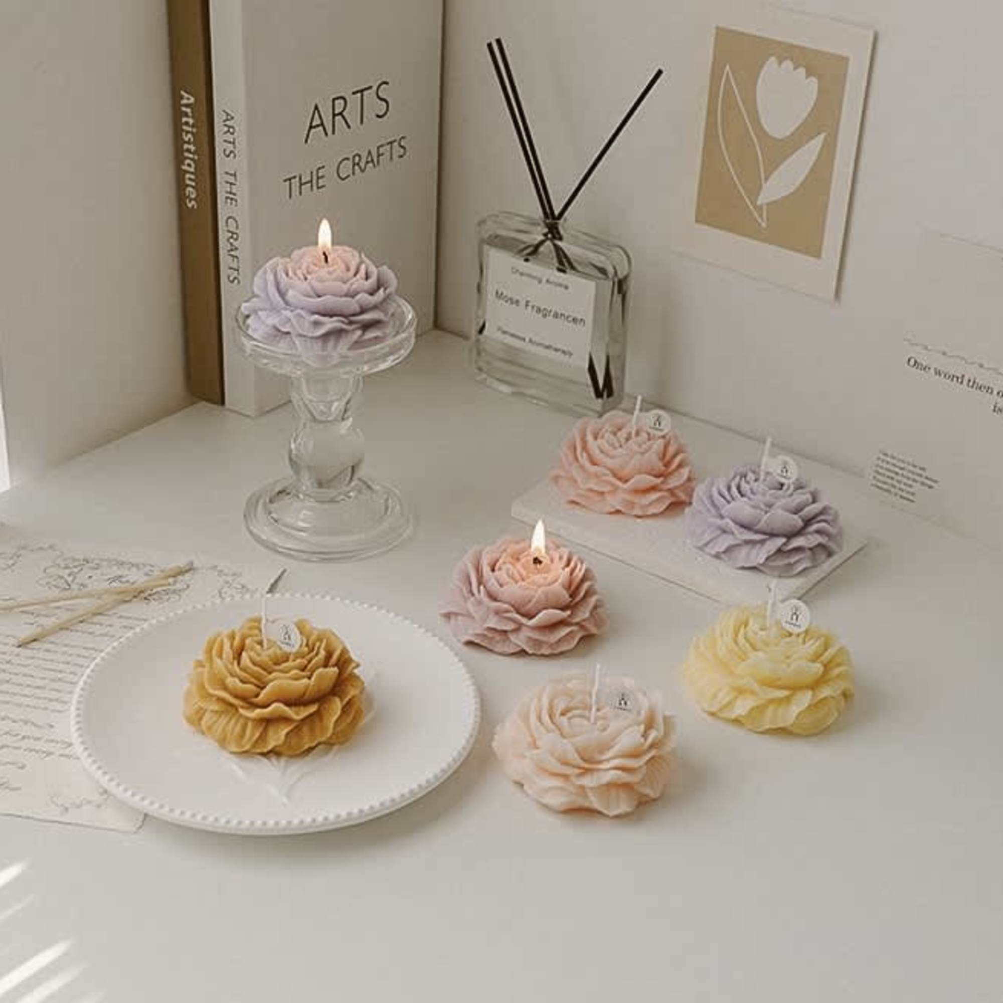 Flower-shaped candles in pastel colors arranged on a white tabletop