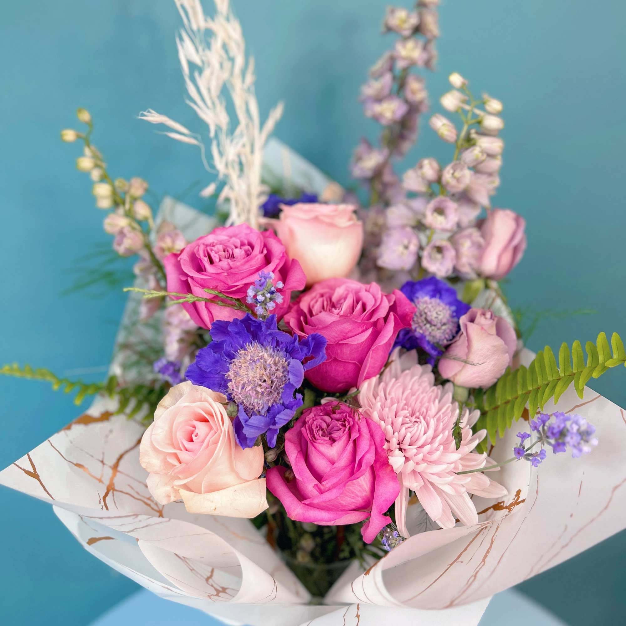 Bouquet of pink and lavender flowers wrapped in white paper
