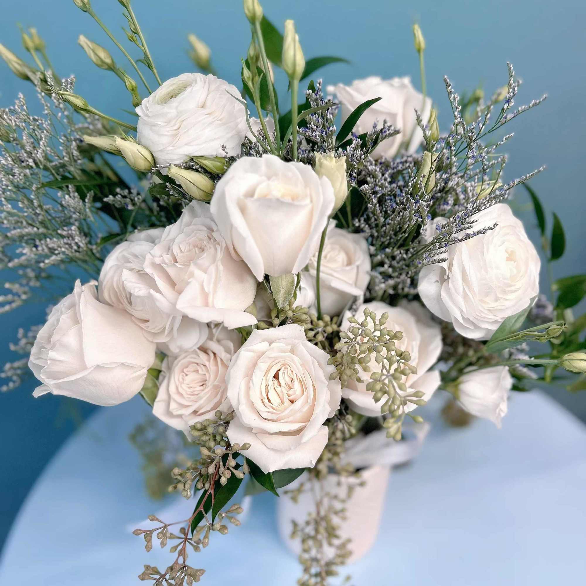 White rose bouquet with airy filler flowers in a white vase