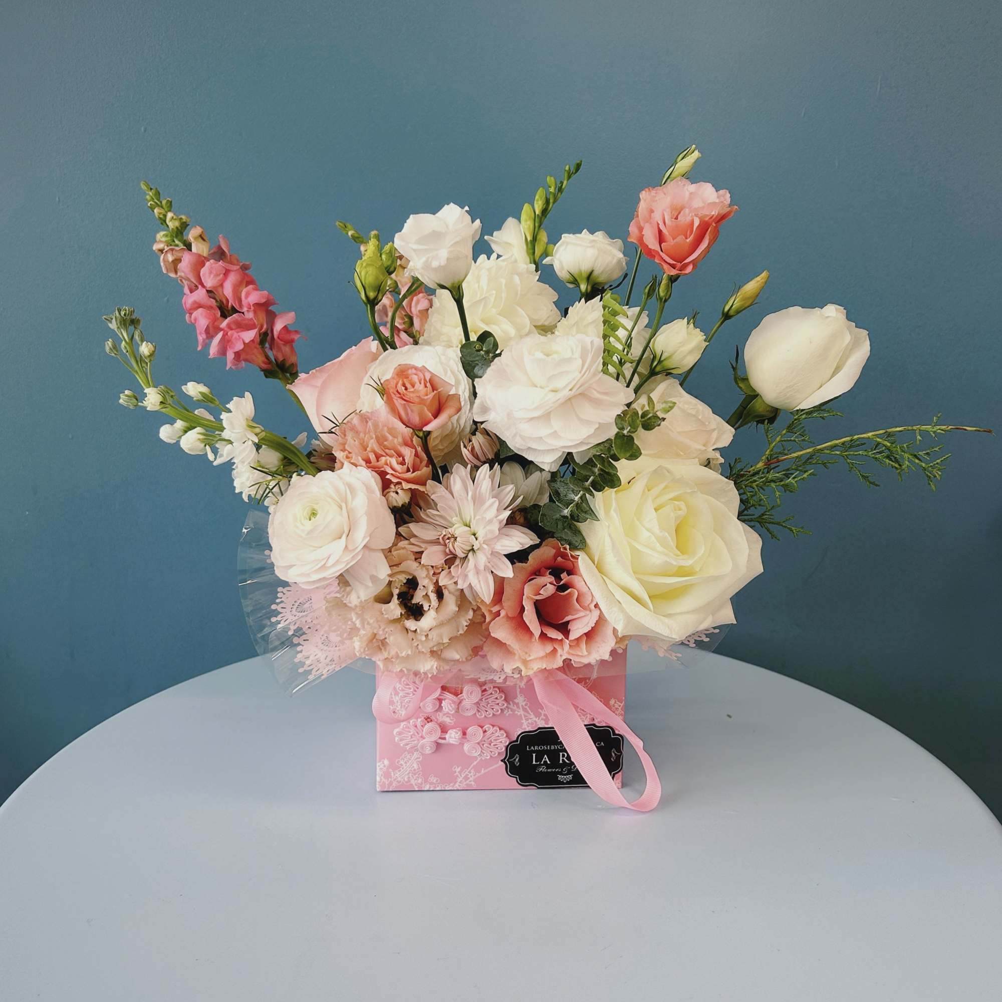 Pink and white mixed flower arrangement in a pink gift box