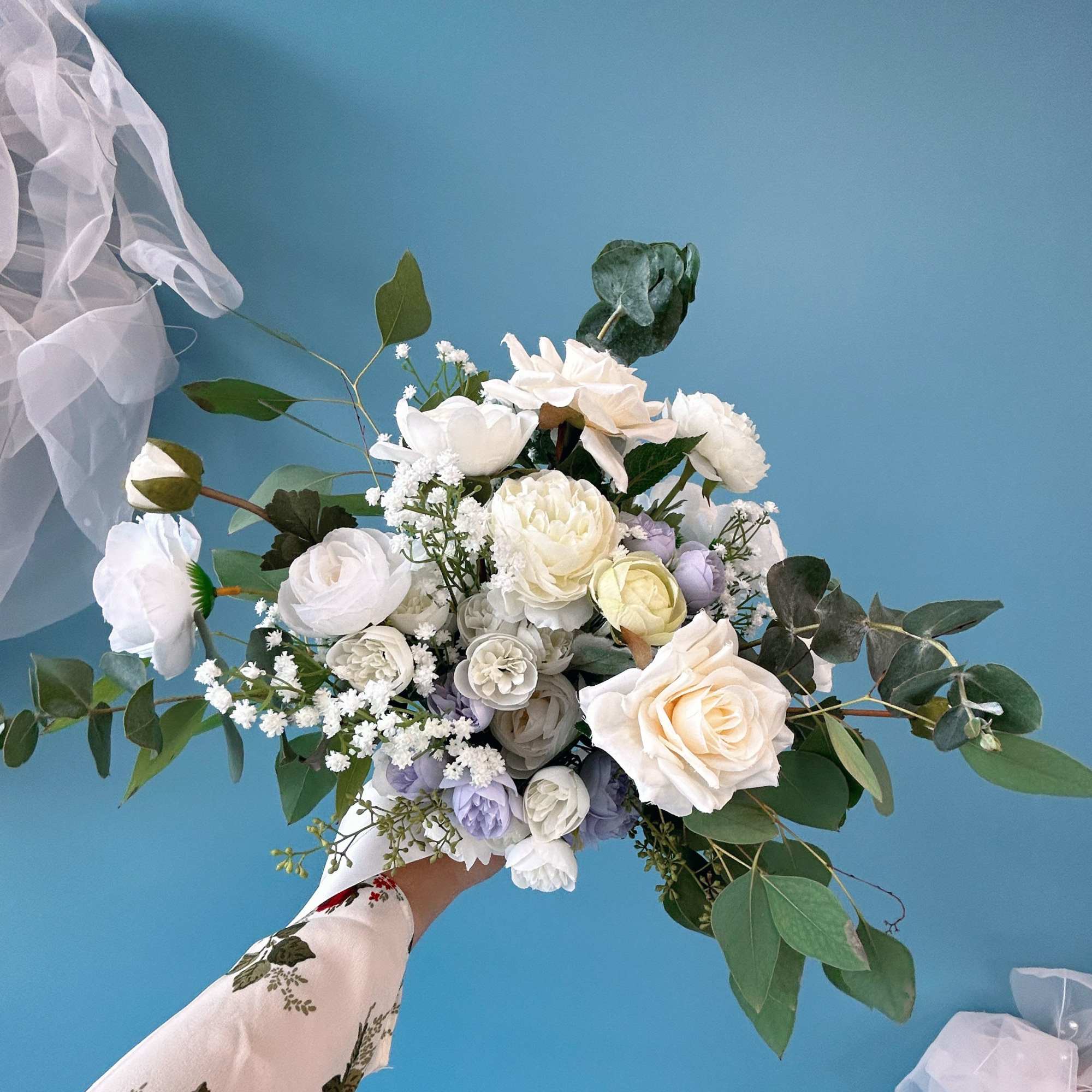 White bridal bouquet with roses and mixed blooms, accented by eucalyptus