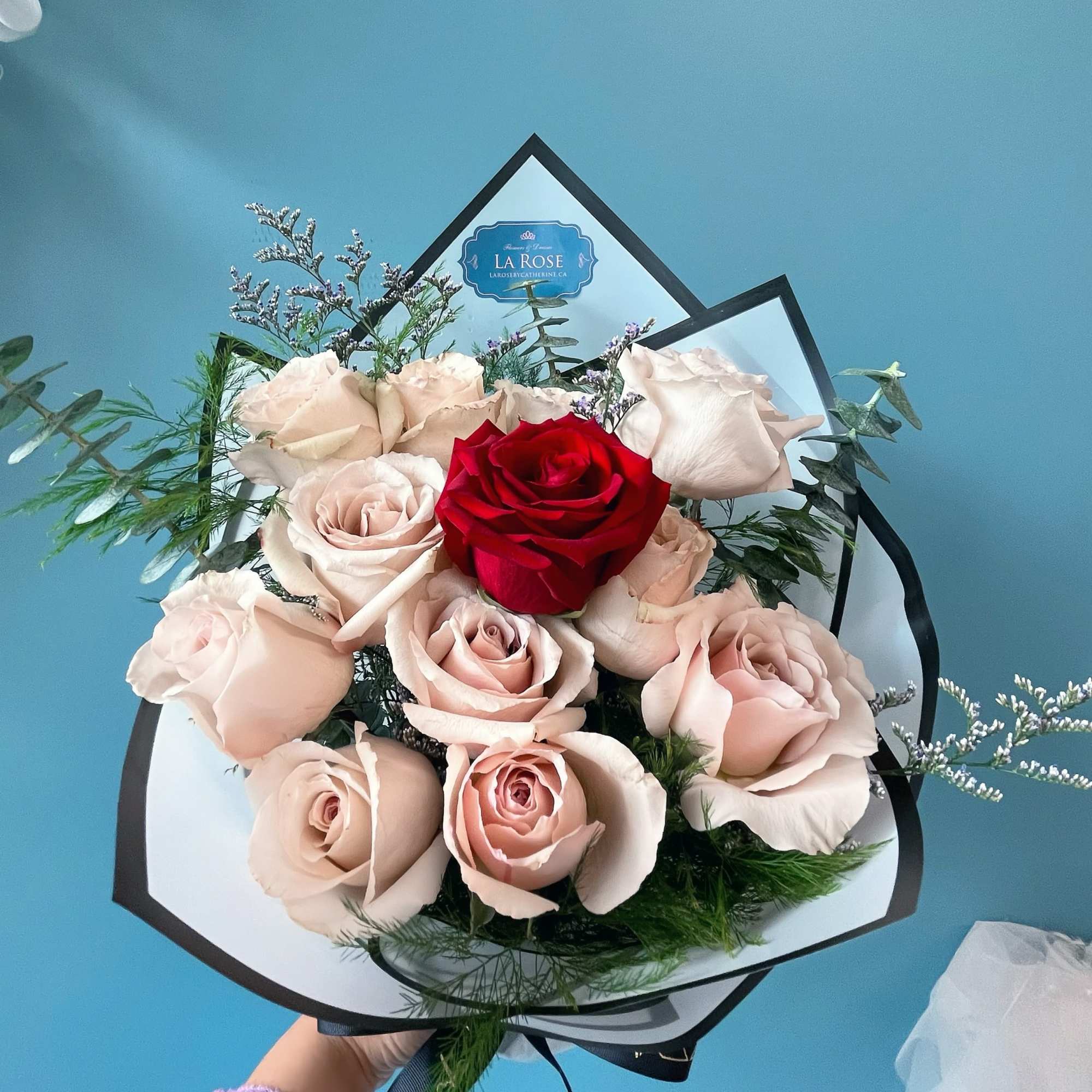 Bouquet of pale pink and red roses wrapped in black paper