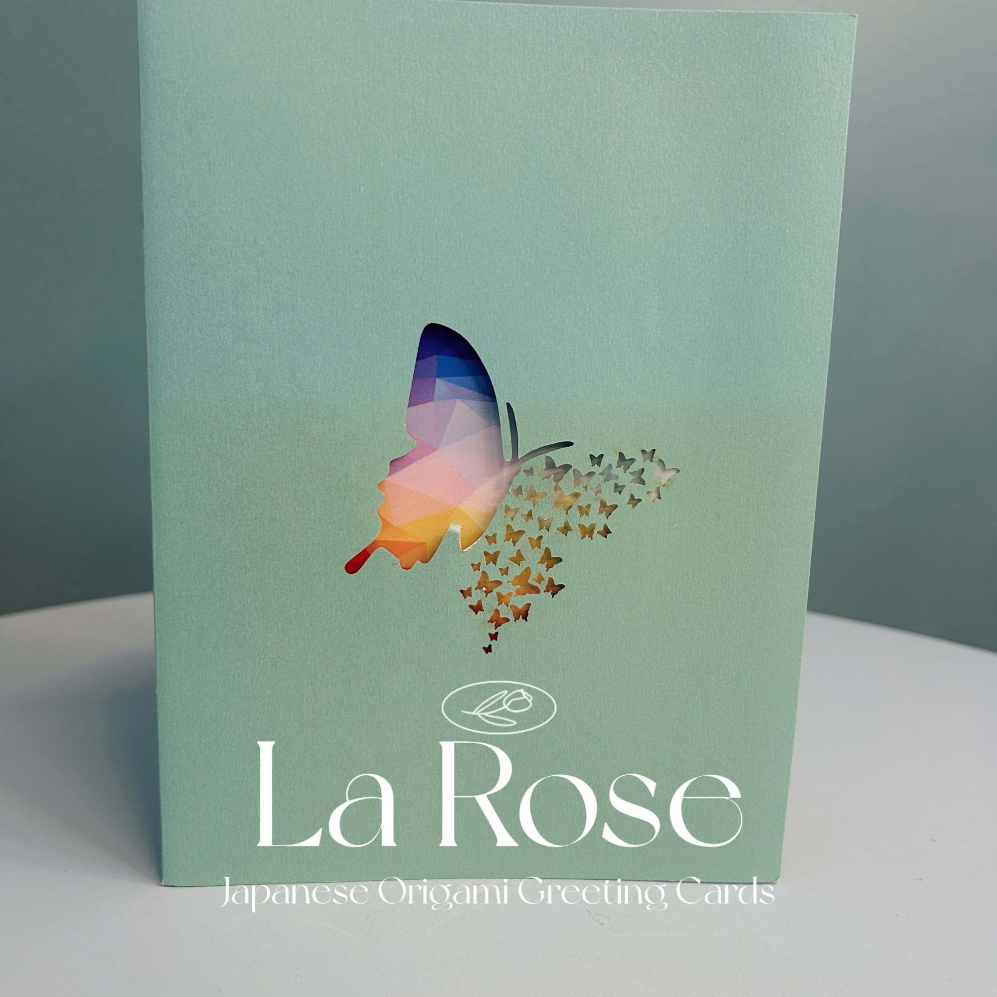 Mint-green greeting card with a colorful butterfly graphic and La Rose text