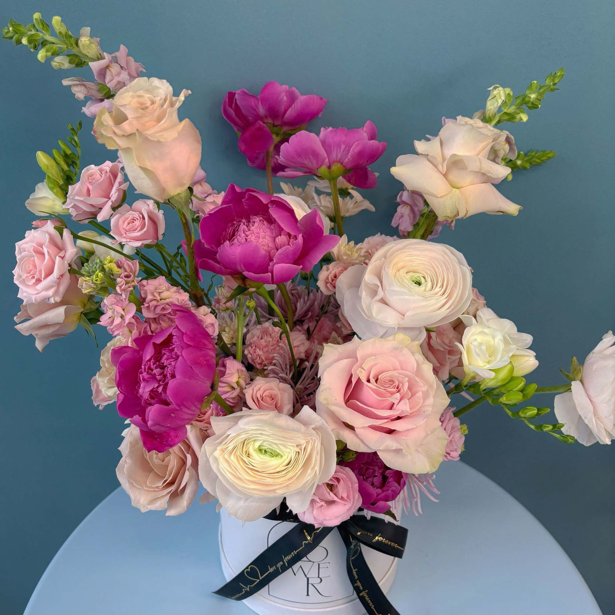 Pink and white mixed bouquet in a white hat box with a black ribbon
