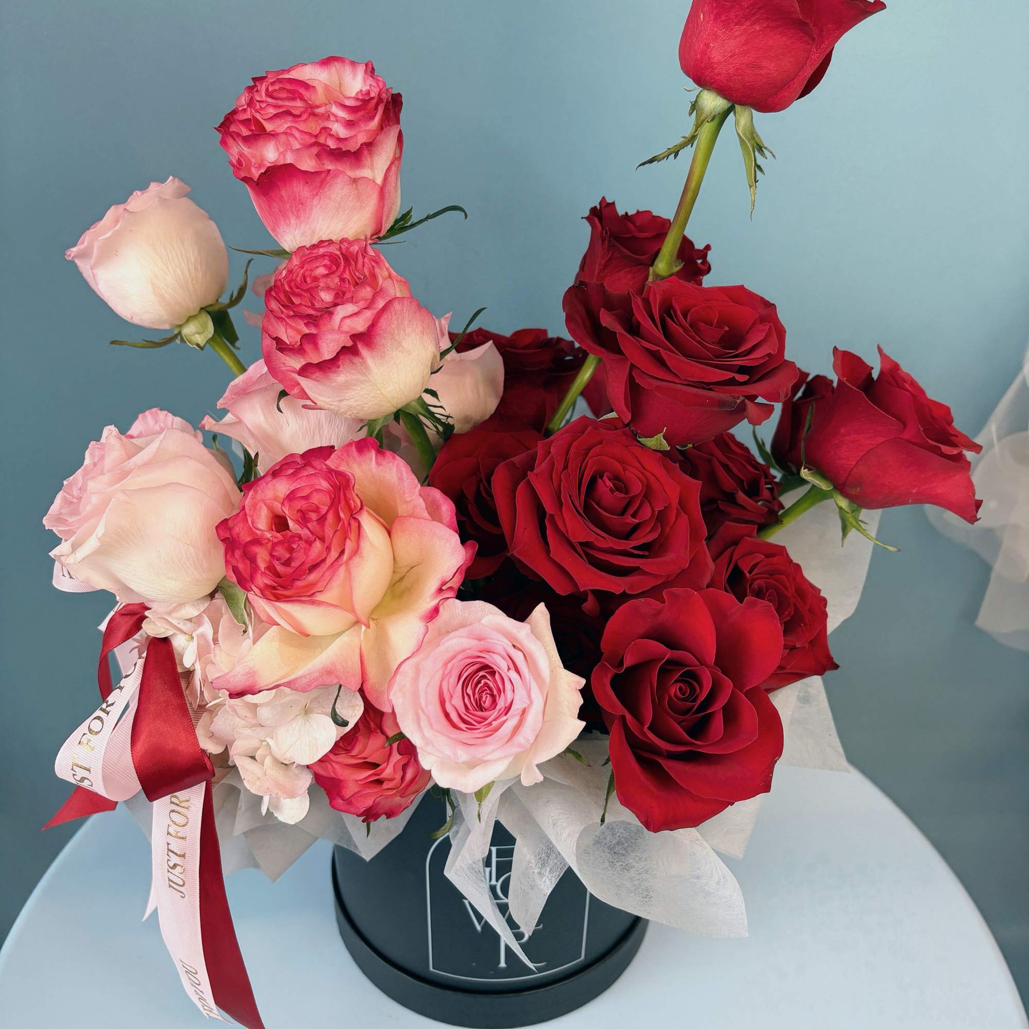 Bouquet of red and pink roses in a black box with ribbon