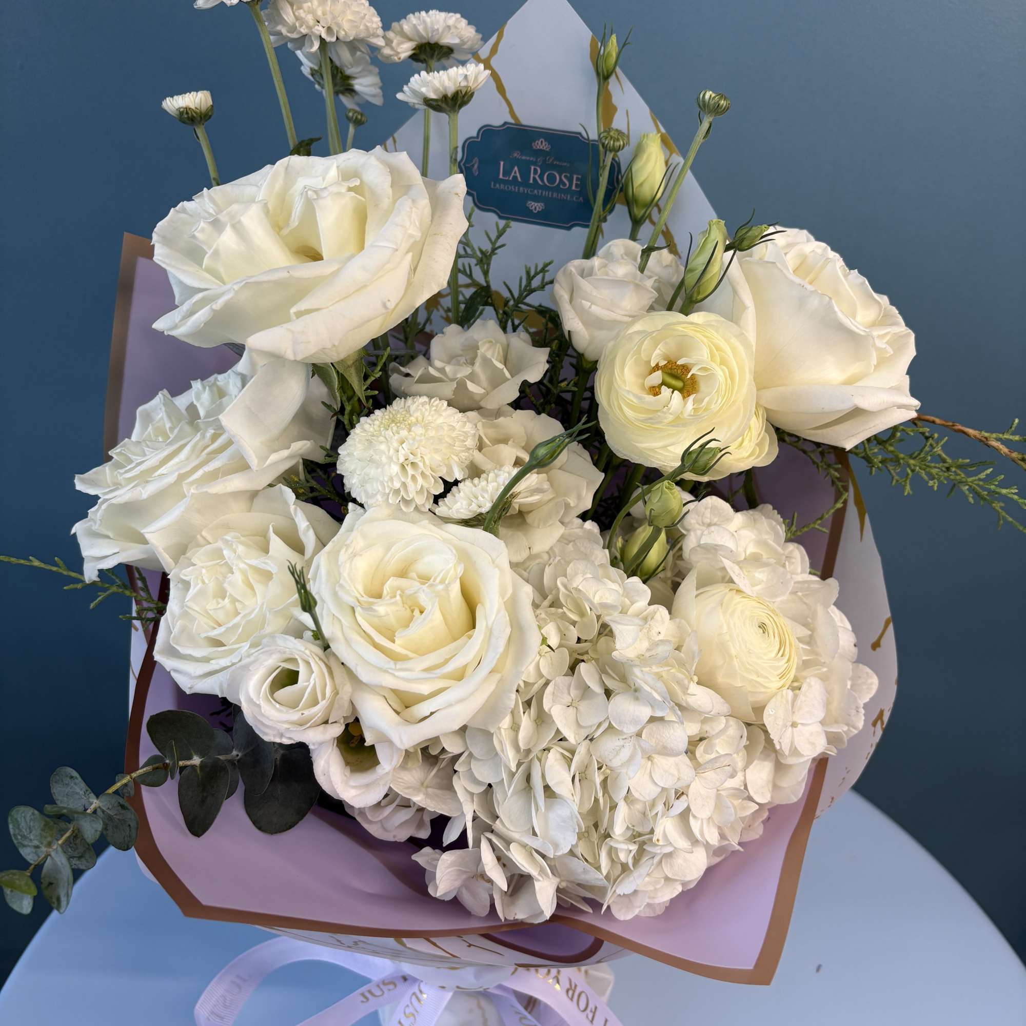 White rose and hydrangea bouquet with small white blooms in pastel wrapping
