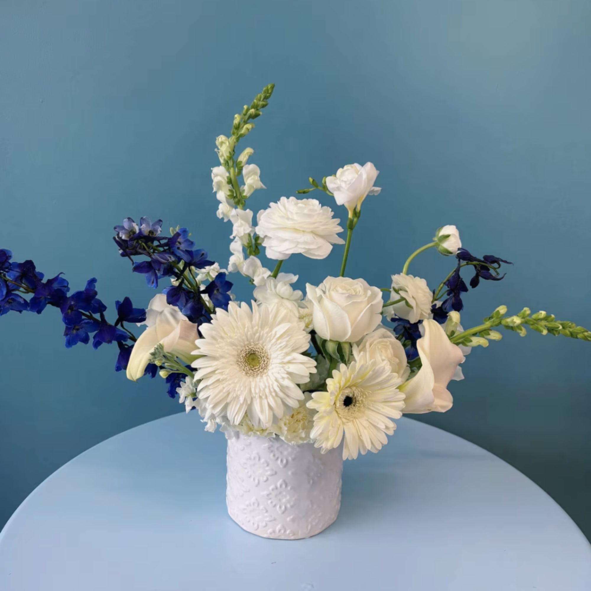 White and blue mixed flower arrangement in a textured white vase