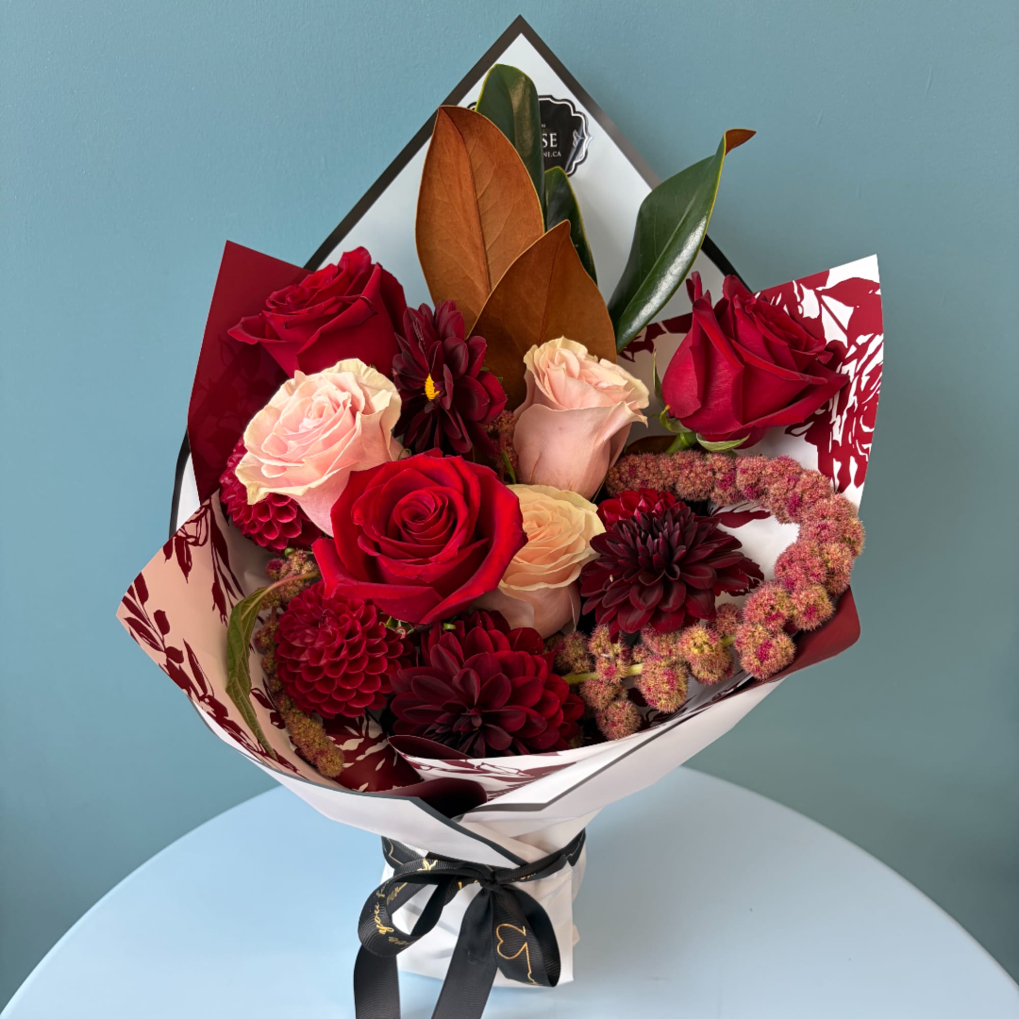 Bouquet of red and blush roses with dark burgundy blooms in wrapped paper