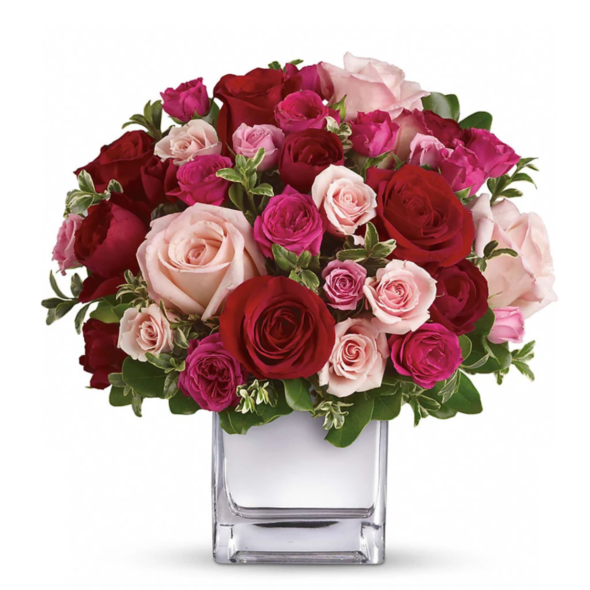 Bouquet of red, pink, and blush roses in a clear square vase