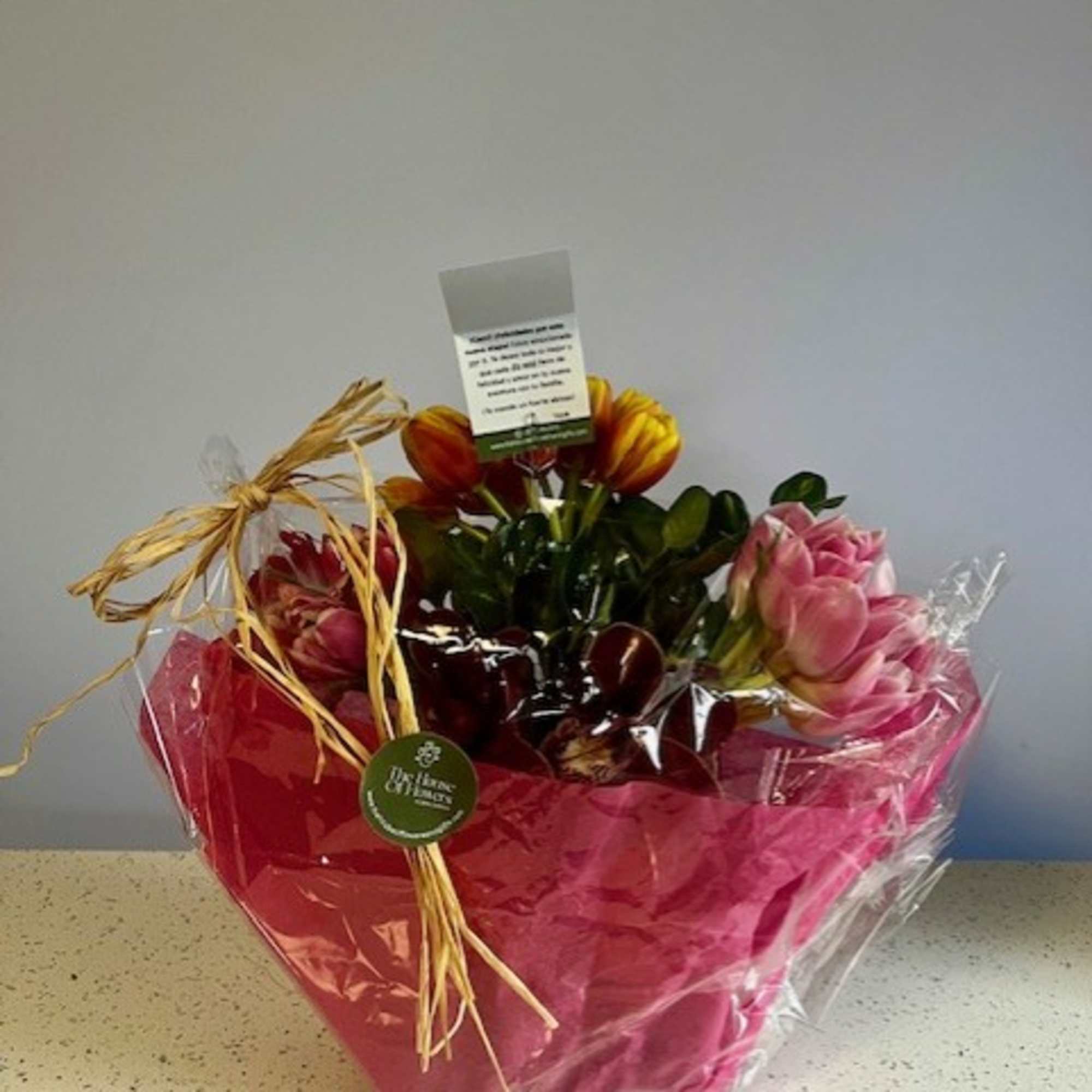Wrapped bouquet with pink and orange tulips in clear plastic