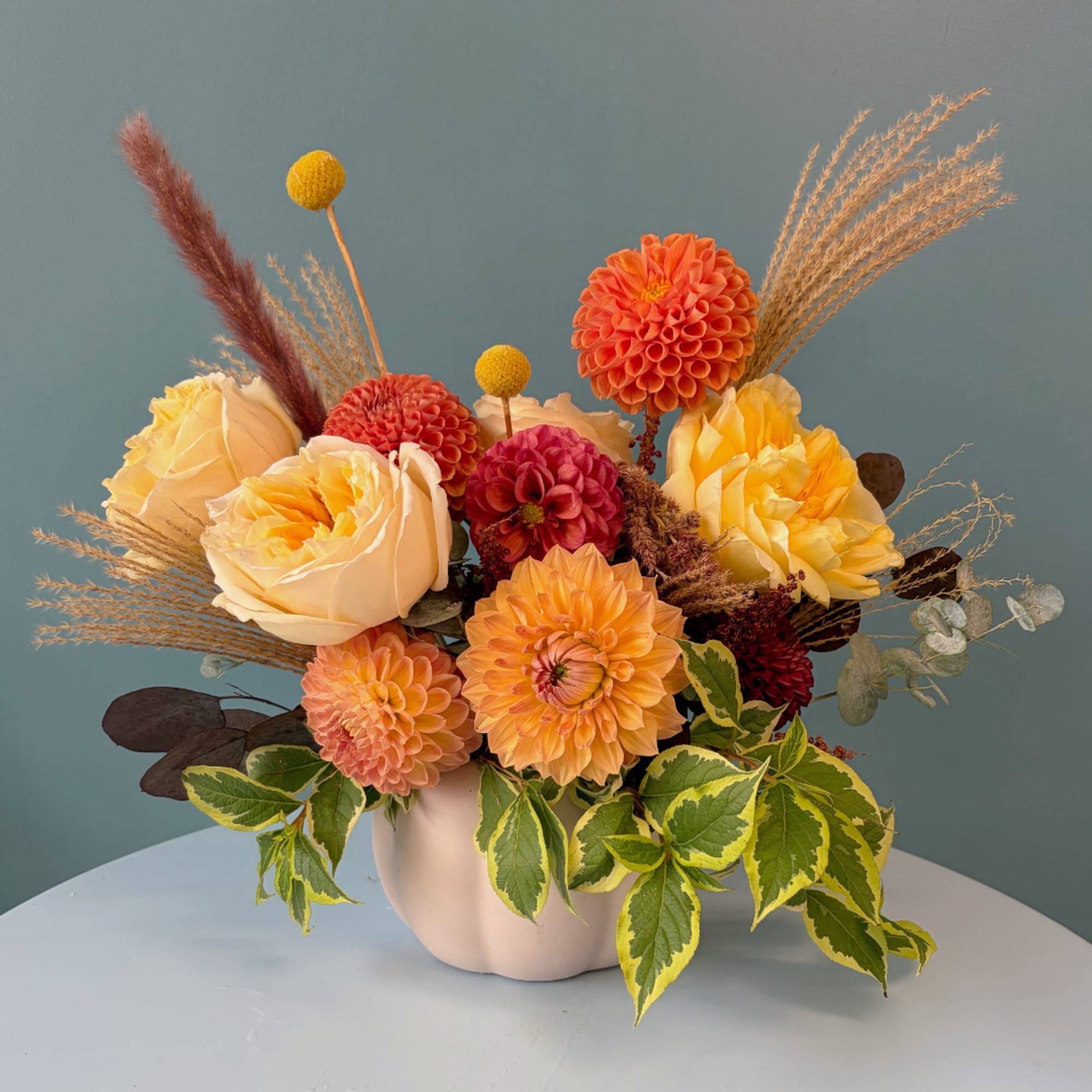 Orange and yellow floral arrangement in a white vase
