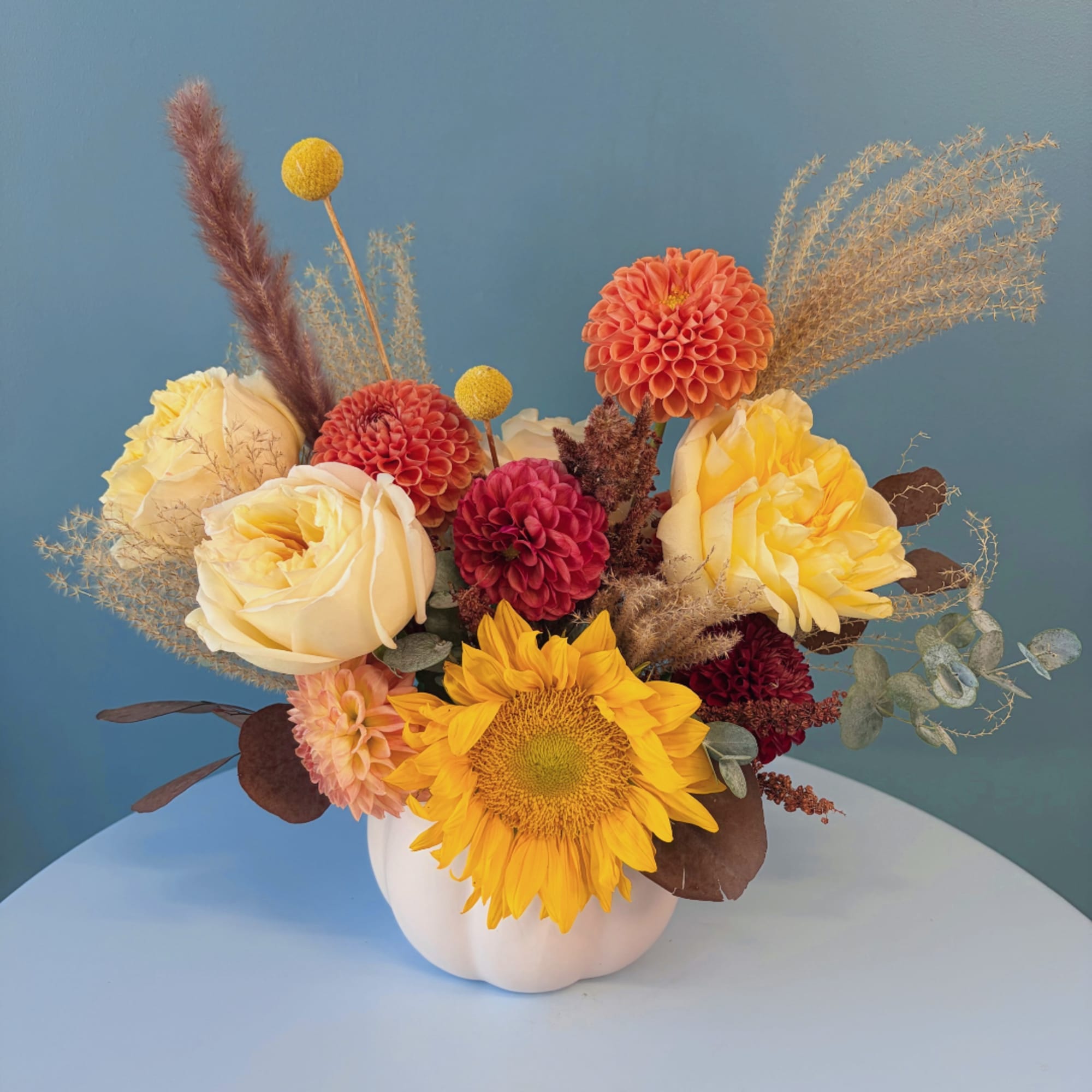 Mixed bouquet with roses, dahlias, and a sunflower in a white vase