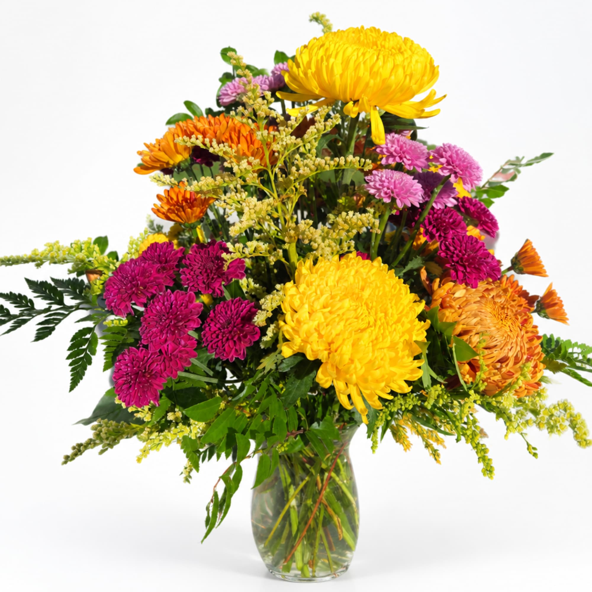 Mixed bouquet of yellow, orange, and pink chrysanthemums in a glass vase