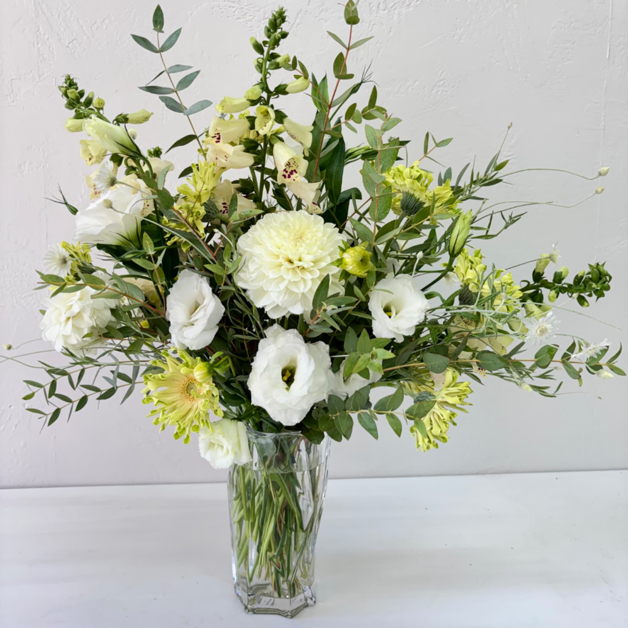 White and pale green floral arrangement in a clear glass vase