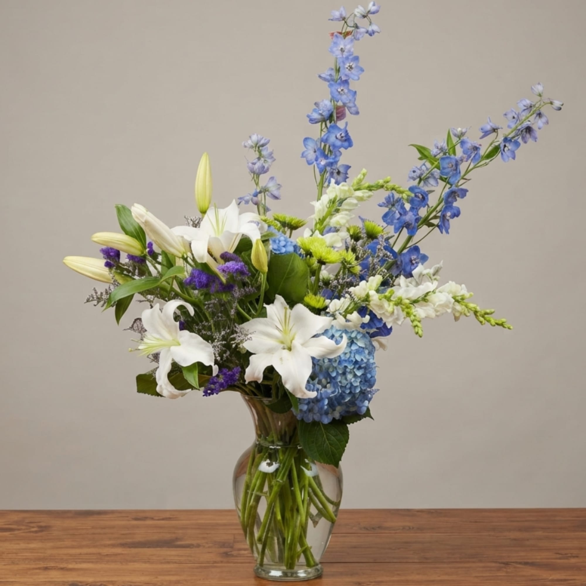 Blue and white mixed flower arrangement in a clear glass vase