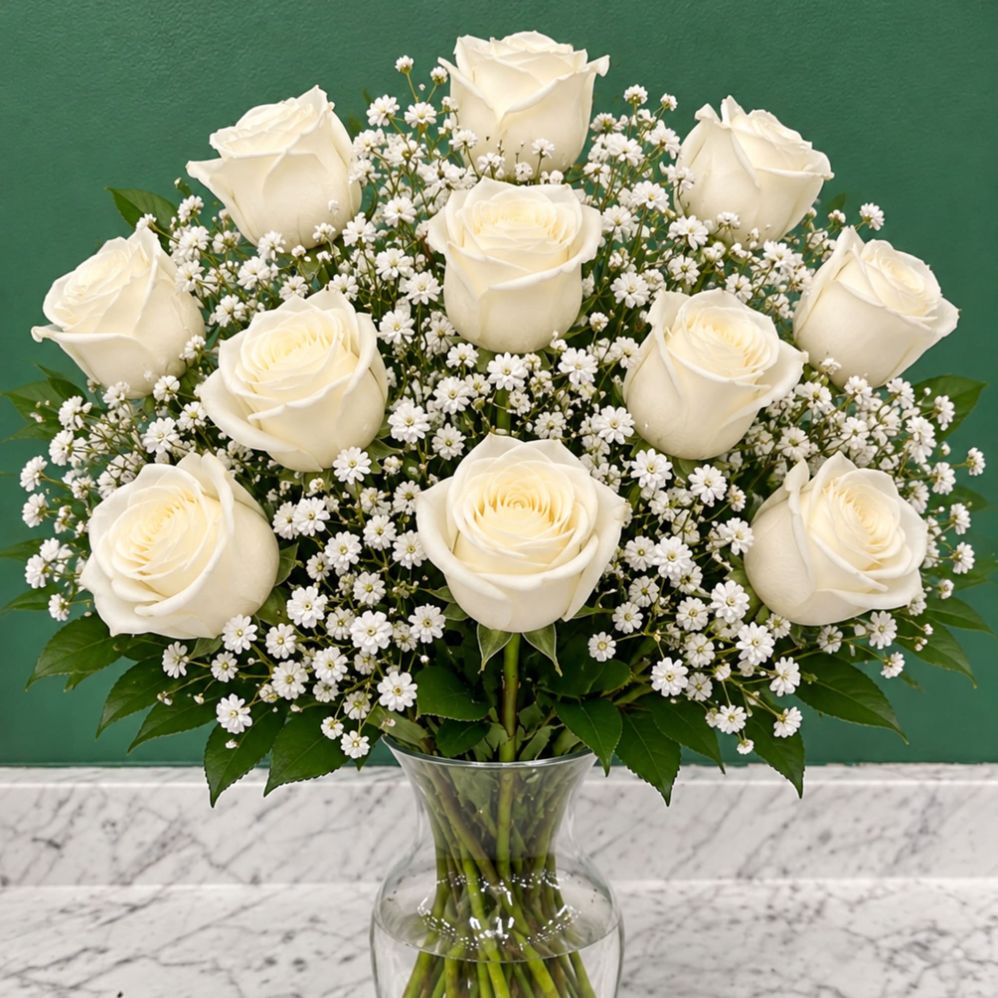 White roses and baby's breath arranged in a clear glass vase