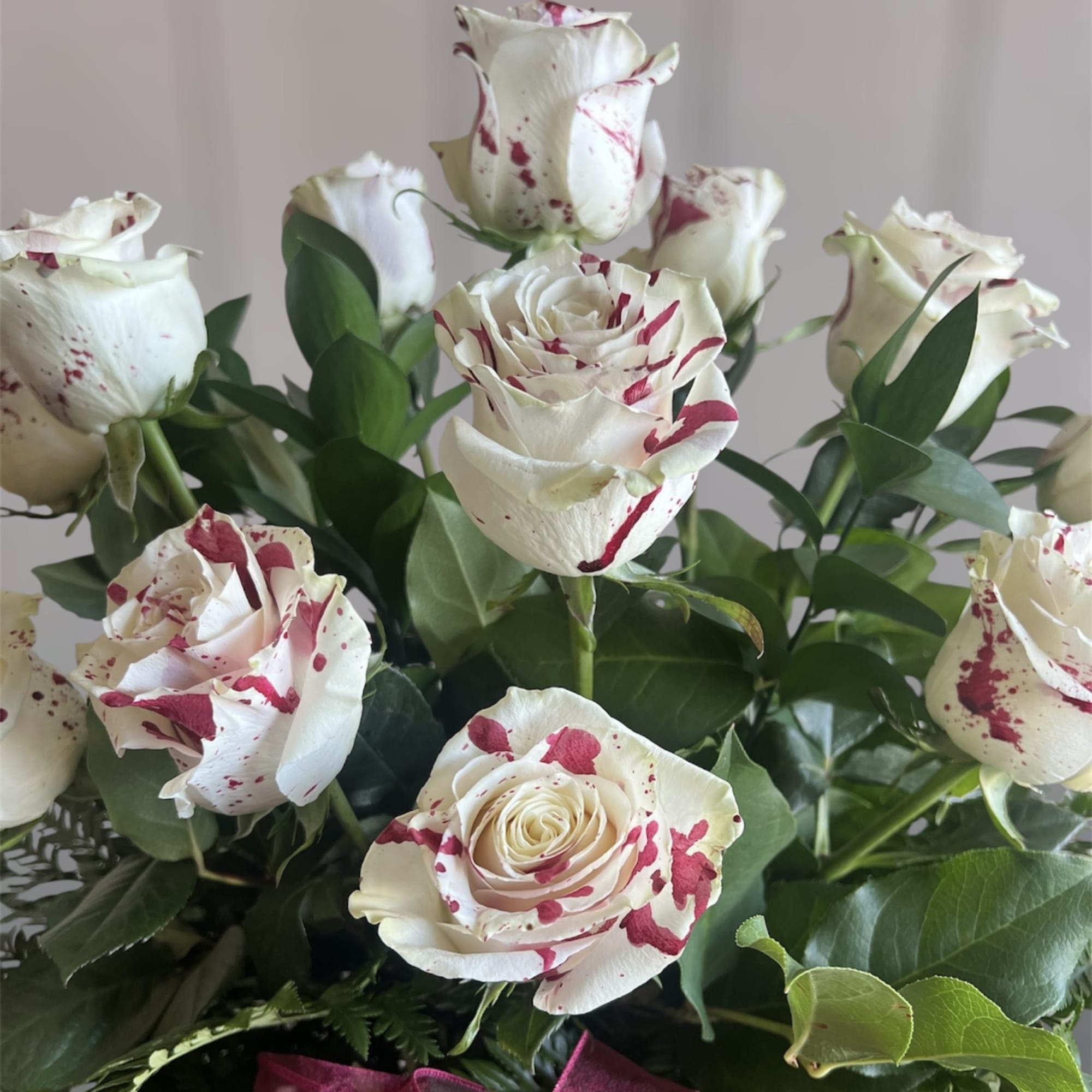 Bouquet of white roses with red speckles and green foliage