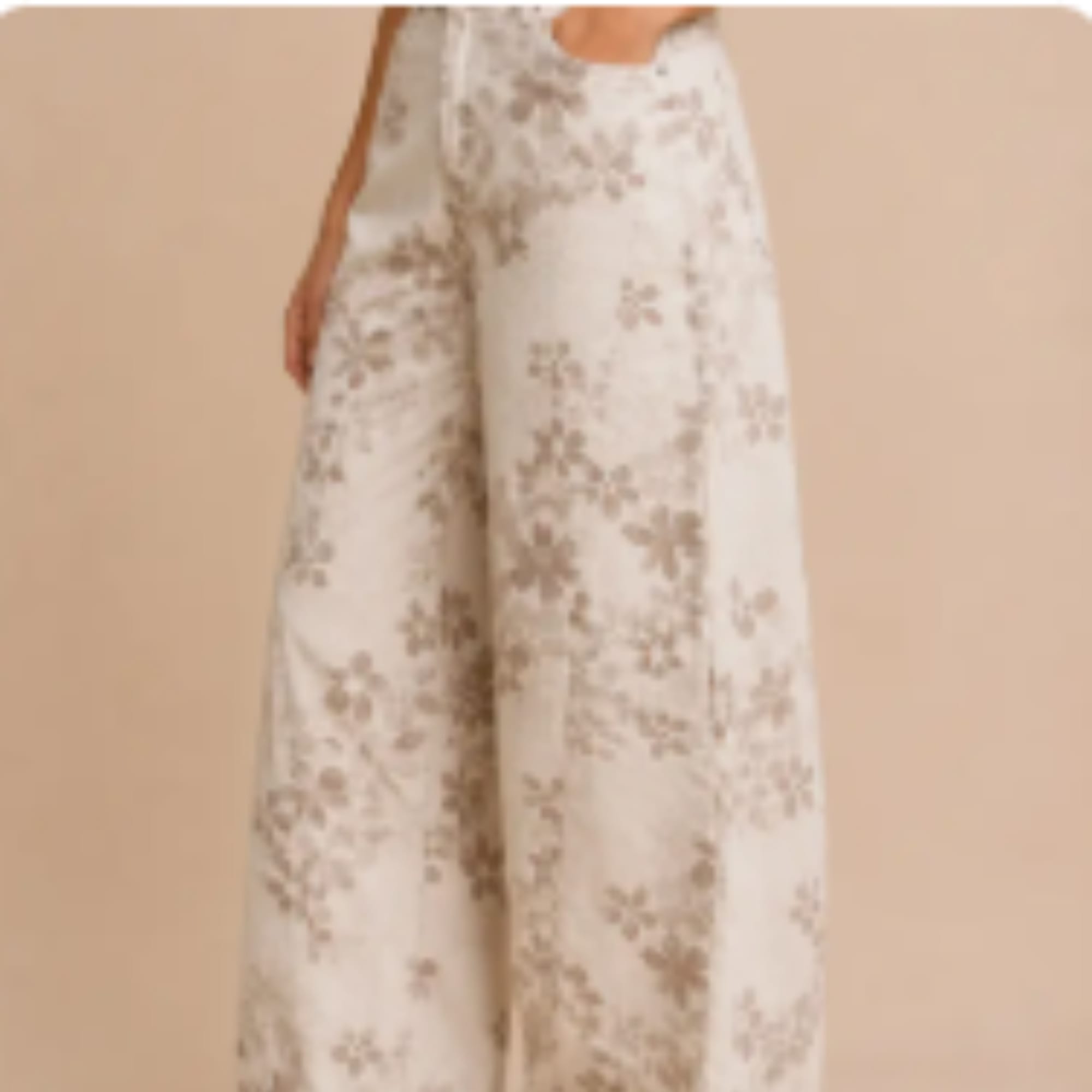 Person wearing cream floral wide-leg pants against a beige background