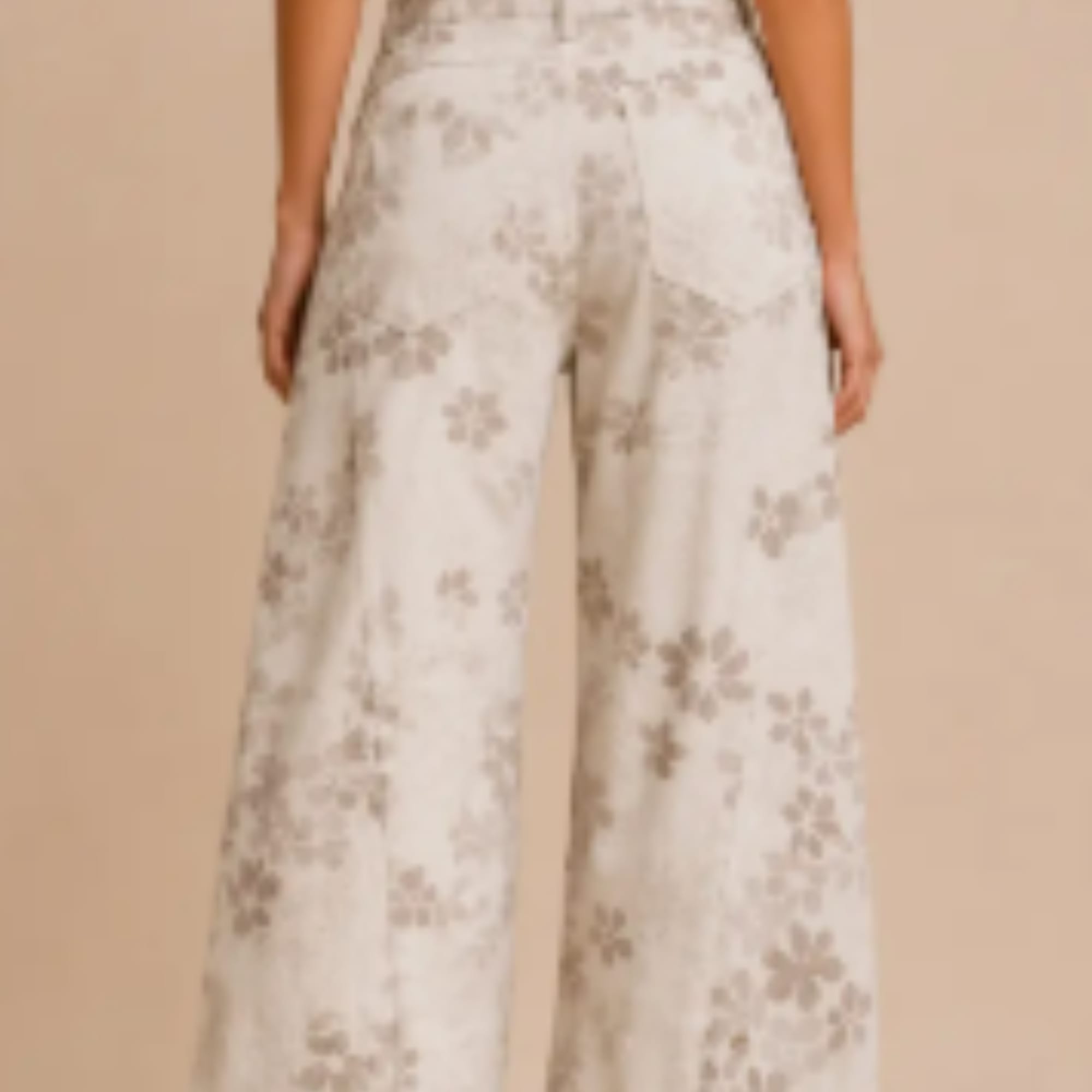 Model wearing cream wide-leg pants with a floral print