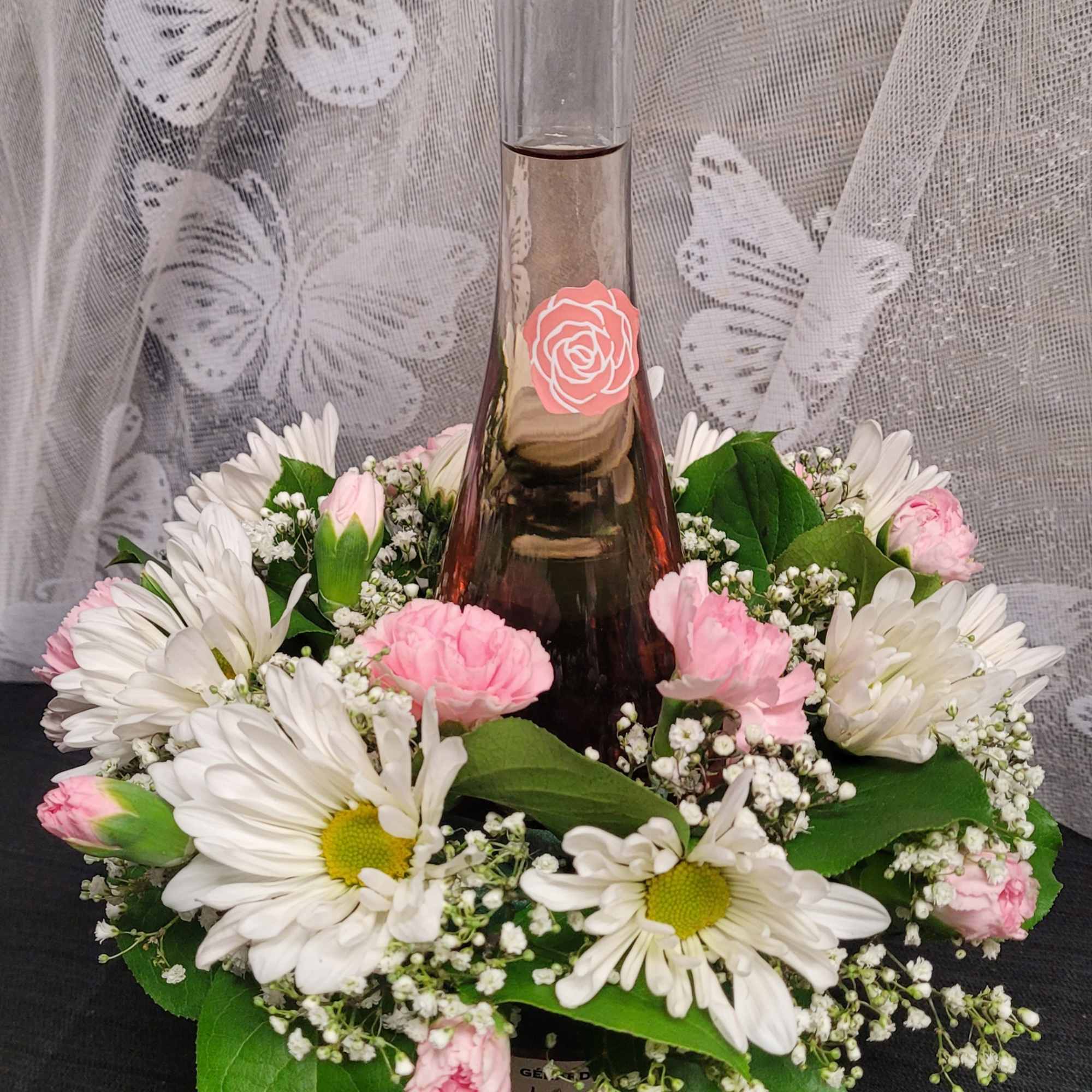 A tall glass bottle of ros&eacute; rises from the center of a