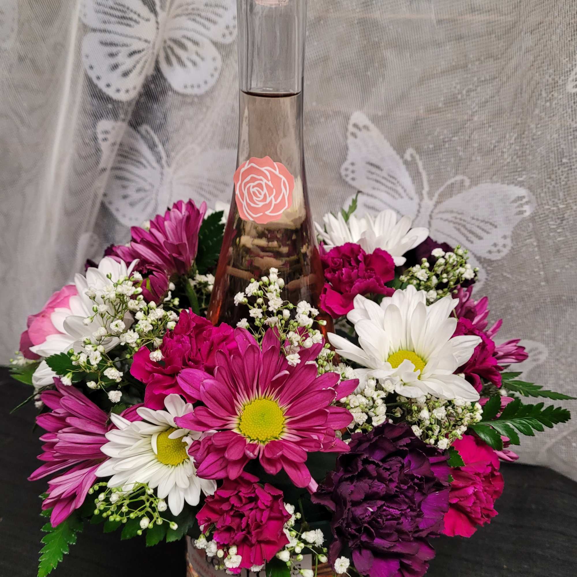 A tall glass bottle of ros&eacute; rises from the center of a