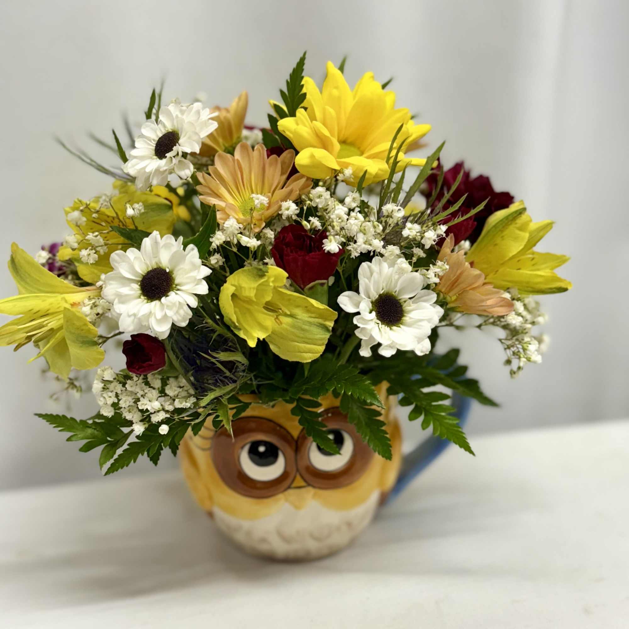 Bouquet of mixed flowers in an owl mug