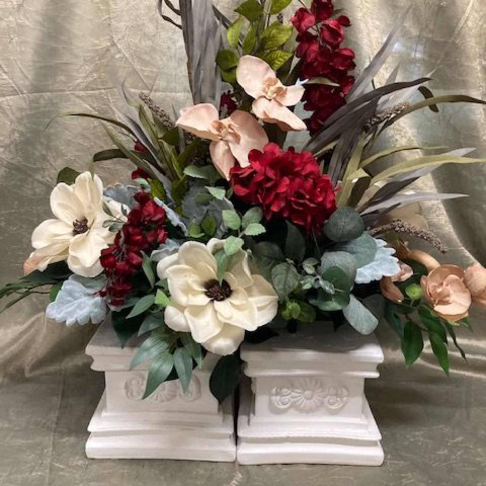 Floral arrangement with cream and burgundy blooms in white pedestal containers