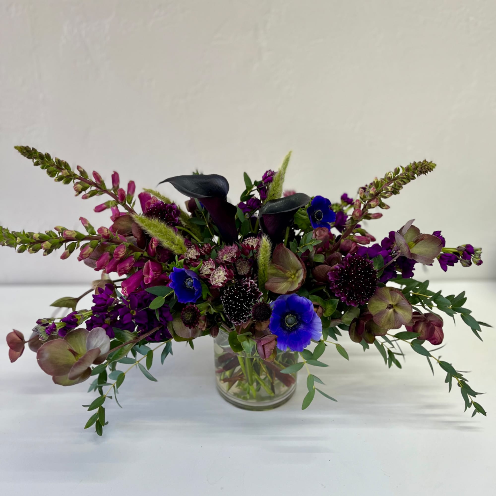 Purple and blue floral arrangement in a clear glass vase, photo 2 of 2