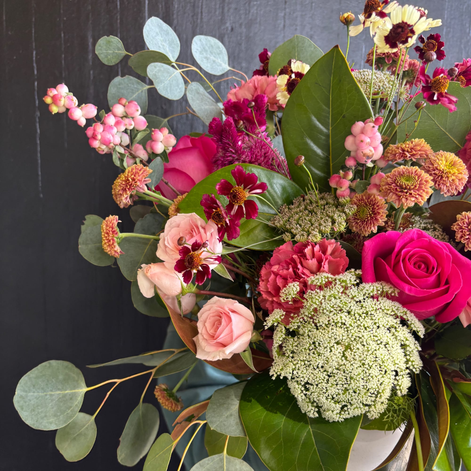 Bouquet of pink and magenta flowers with eucalyptus in a white vase