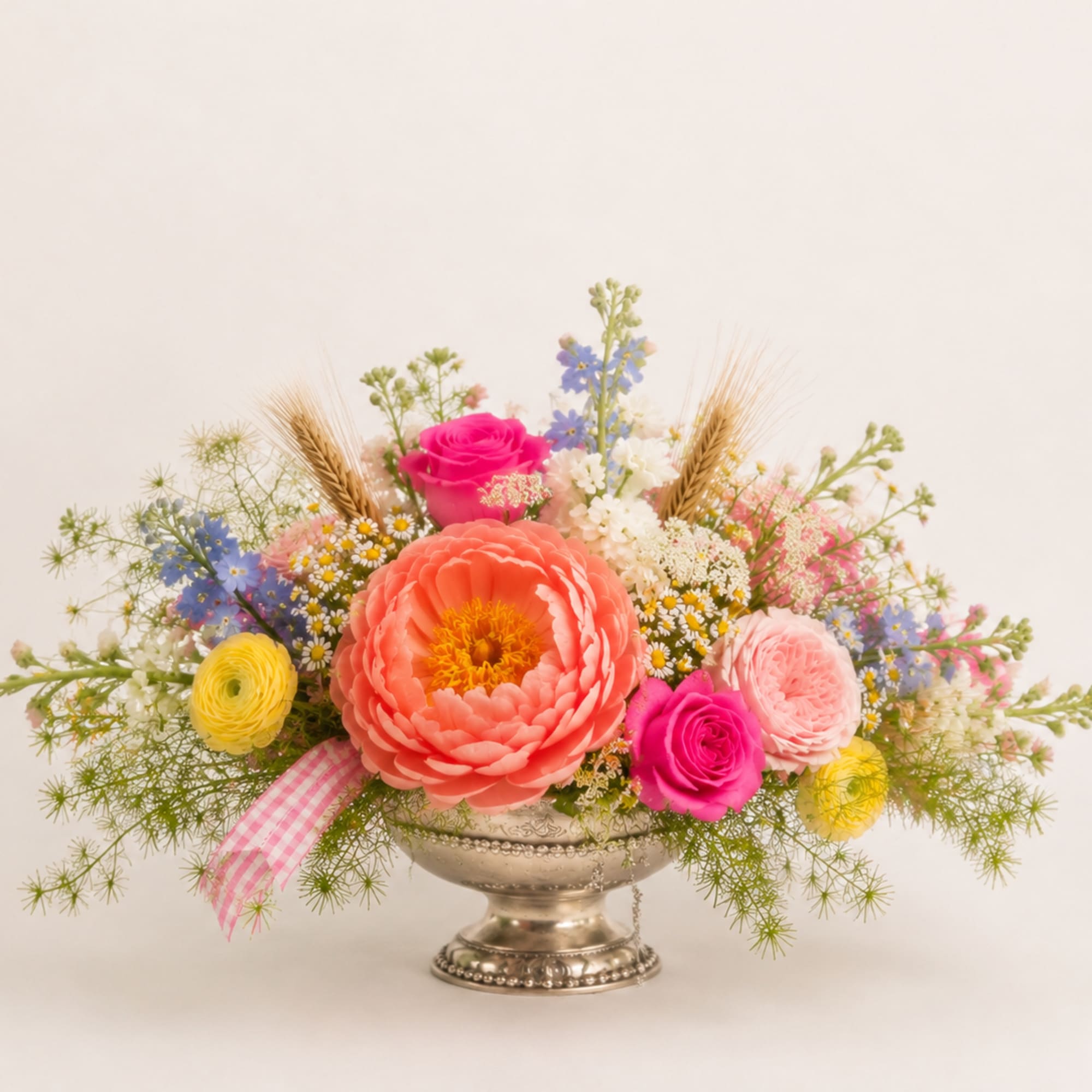 Colorful mixed flower arrangement in a silver pedestal vase