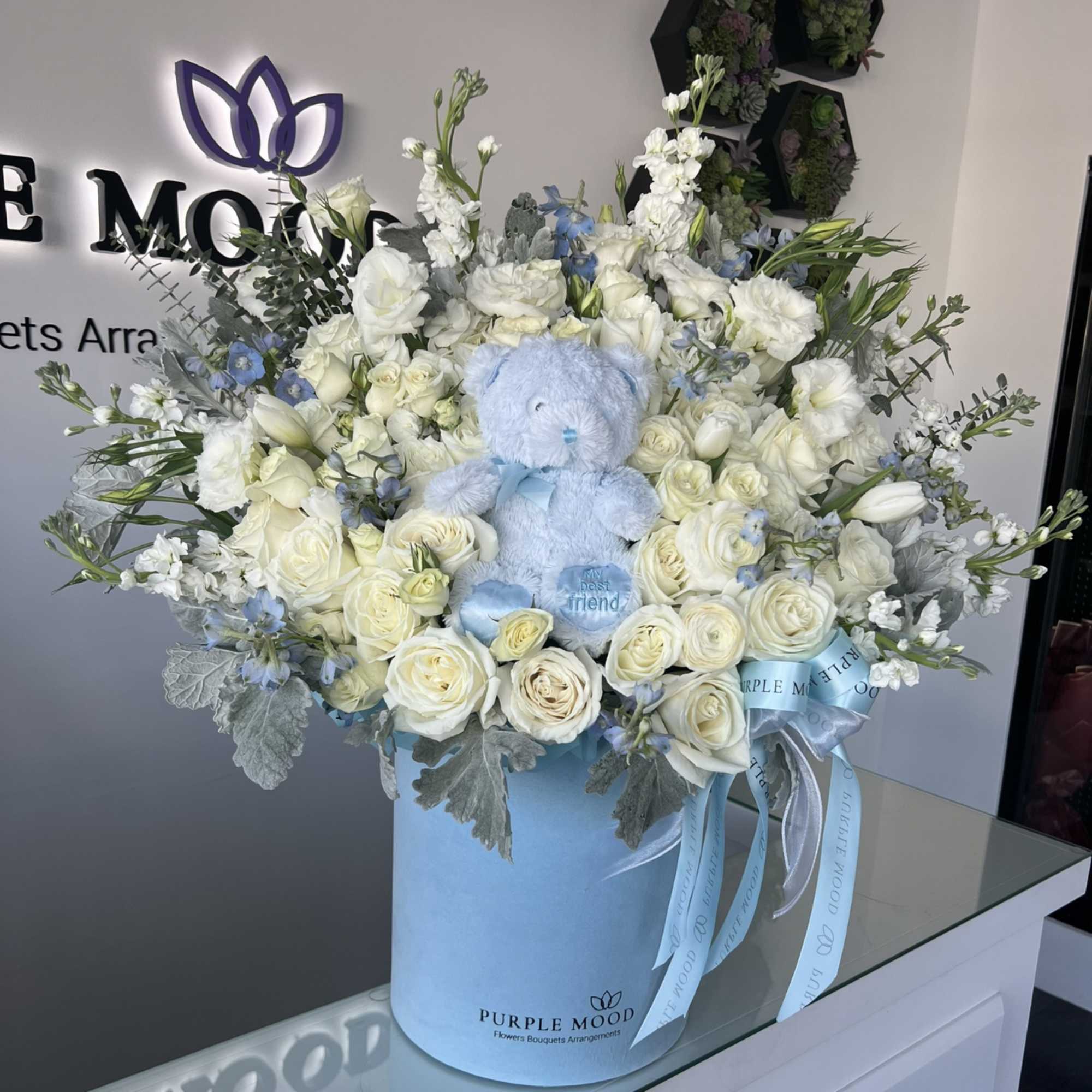 White rose bouquet in a blue hatbox with a light blue teddy bear