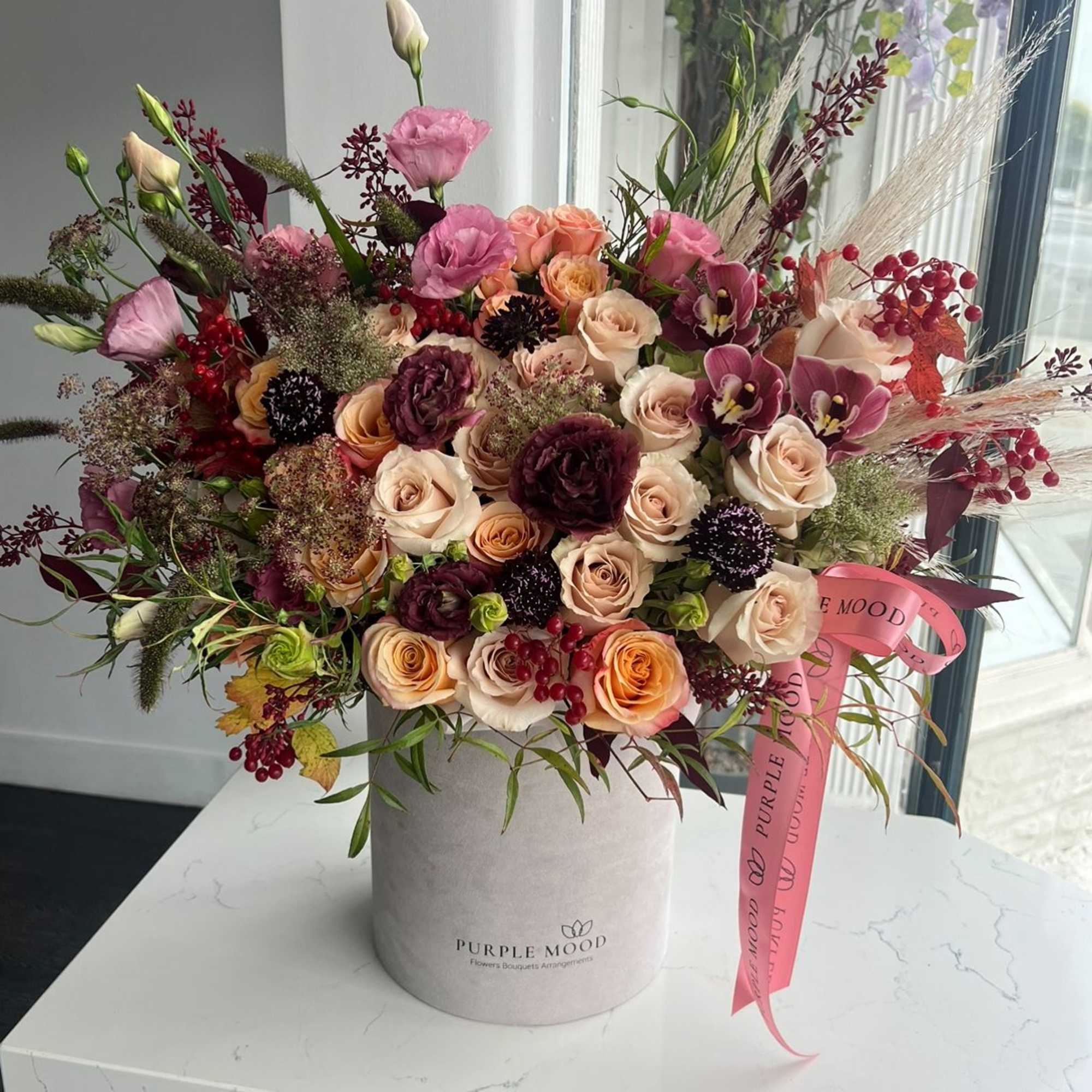 Mixed pink and cream roses in a round hatbox with a ribbon