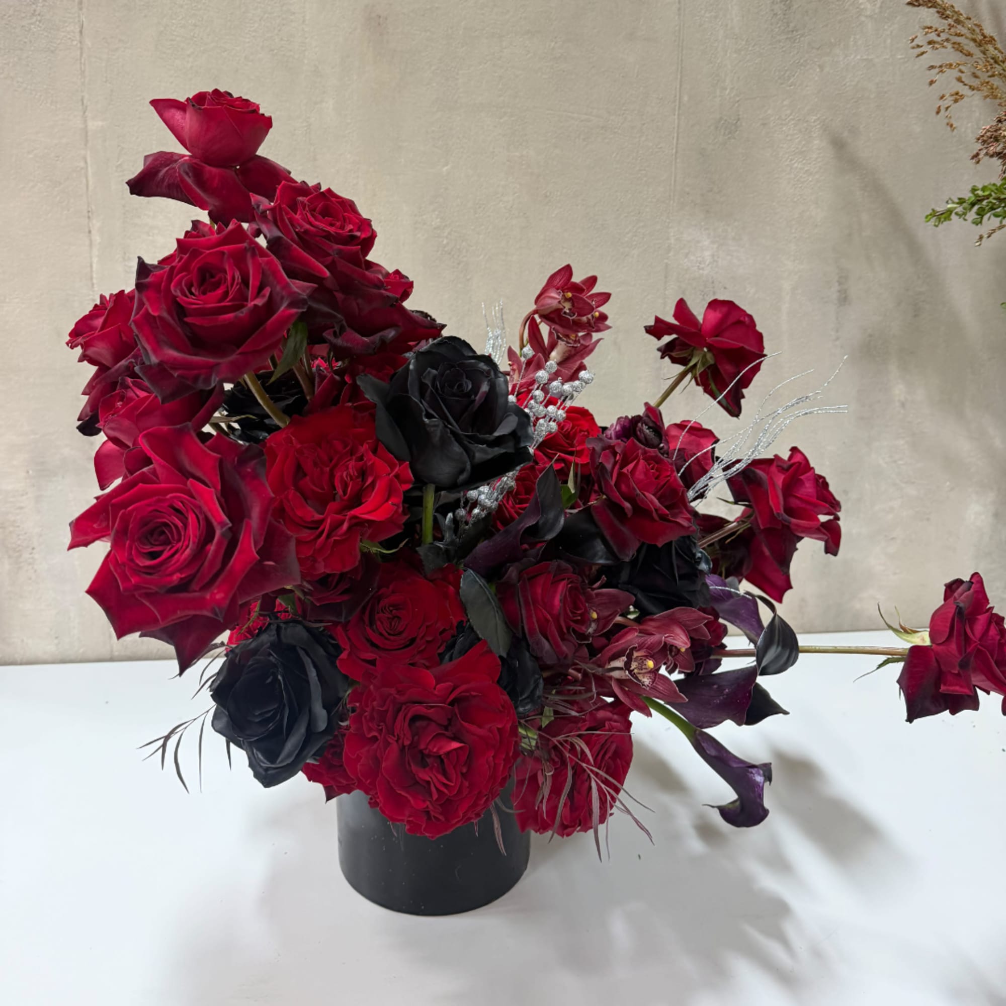 Red and black rose arrangement in a black vase