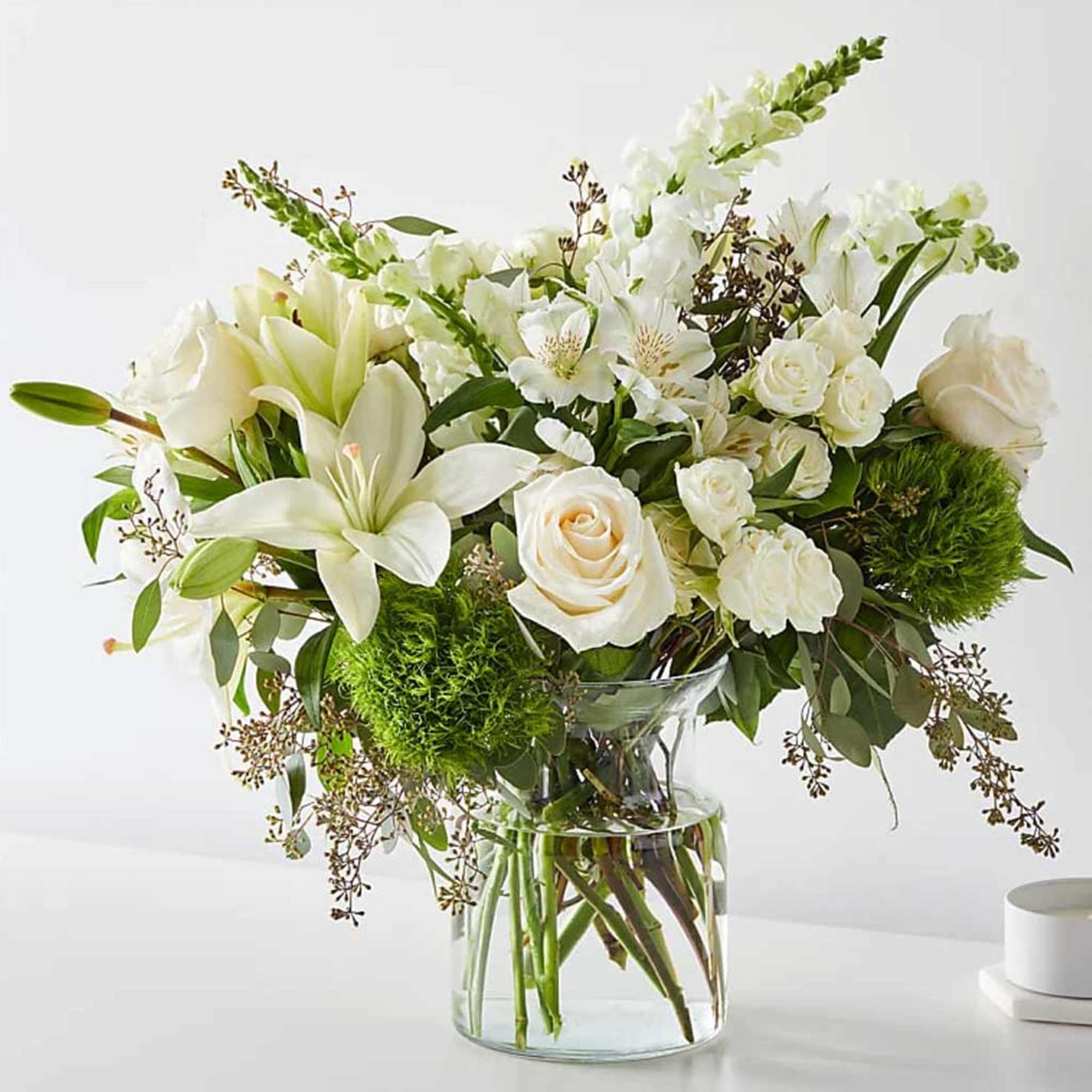 White lilies and roses arranged in a clear glass vase