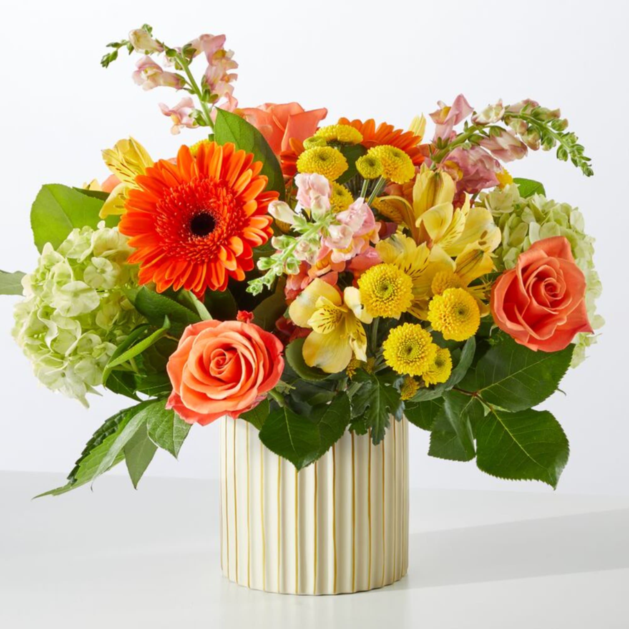 Mixed bouquet of orange, yellow, and pink flowers in a striped vase