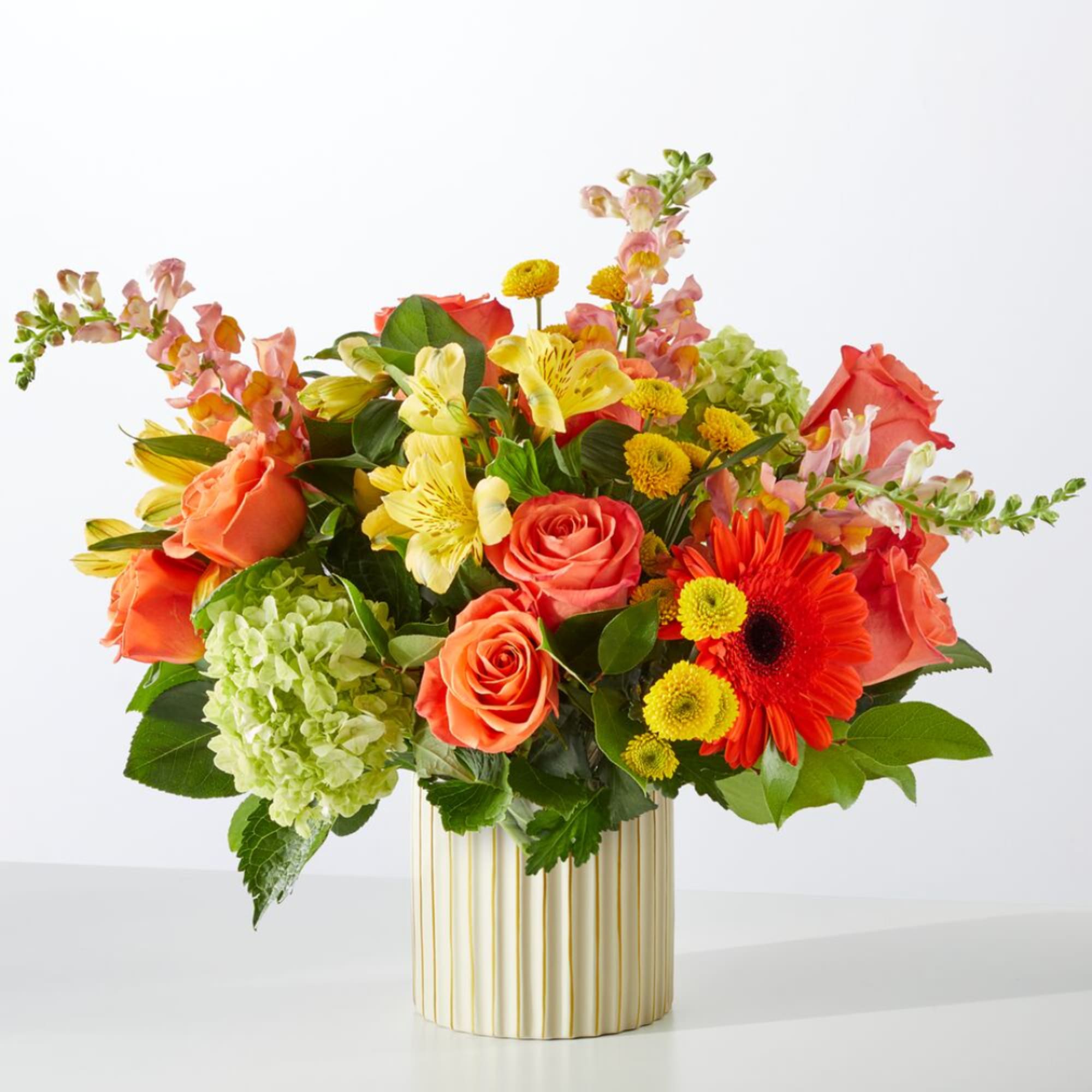 Mixed bouquet of orange and yellow flowers in a striped vase