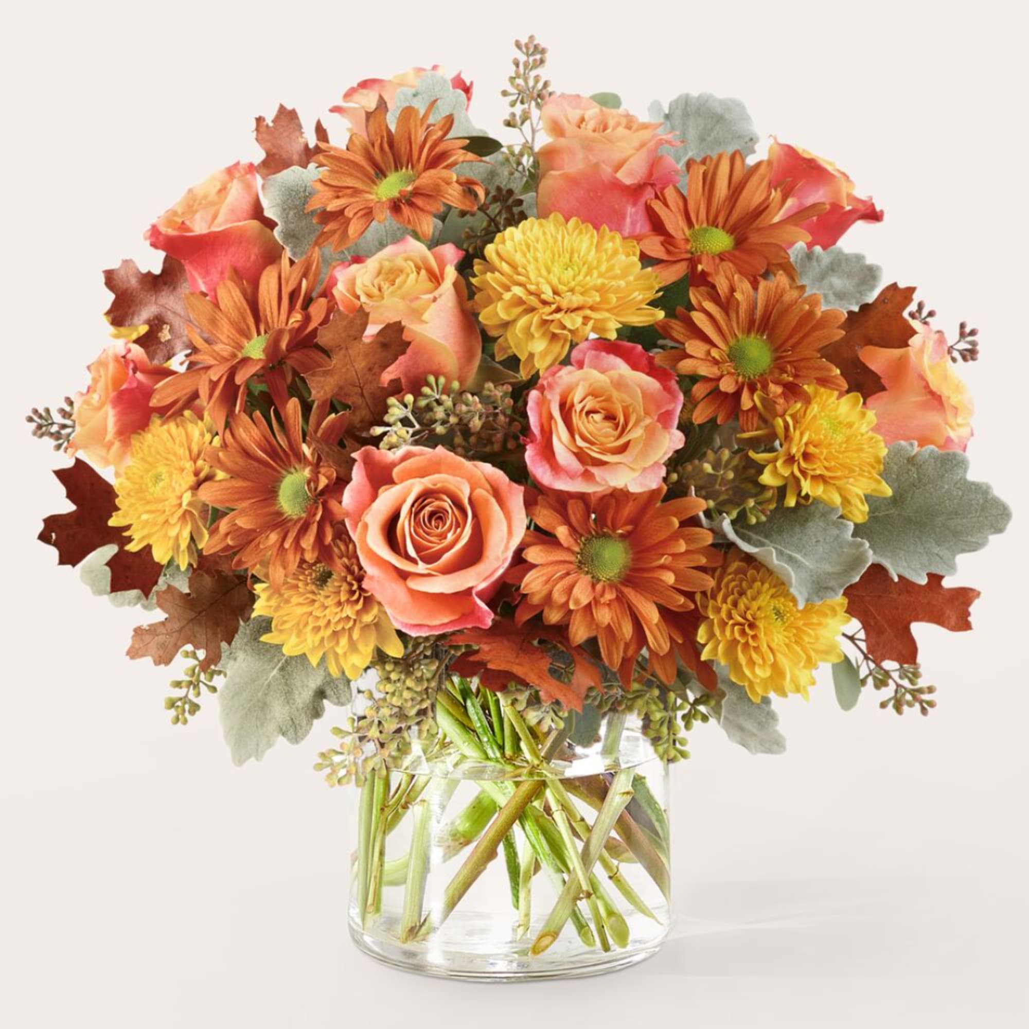 Autumn bouquet of orange roses and yellow mums in a clear glass vase