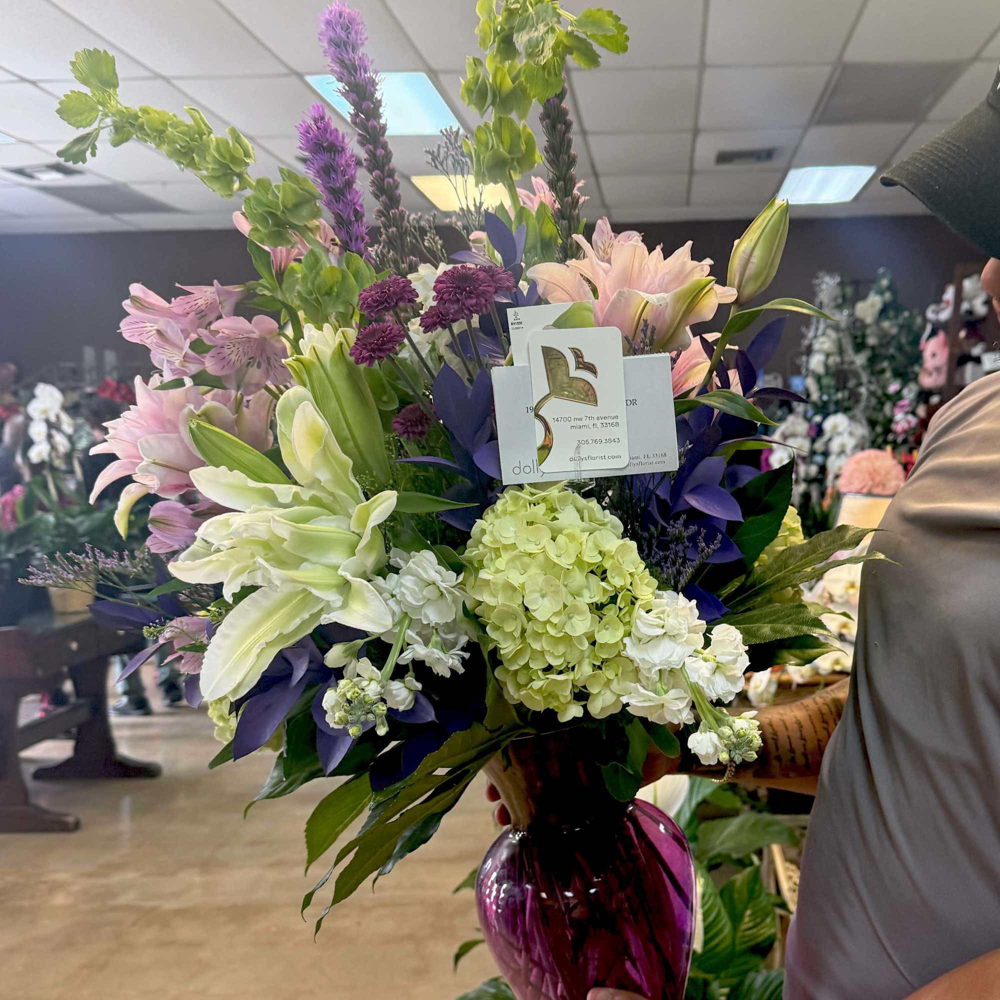 Tall mixed bouquet in a purple glass vase with lilies and hydrangeas