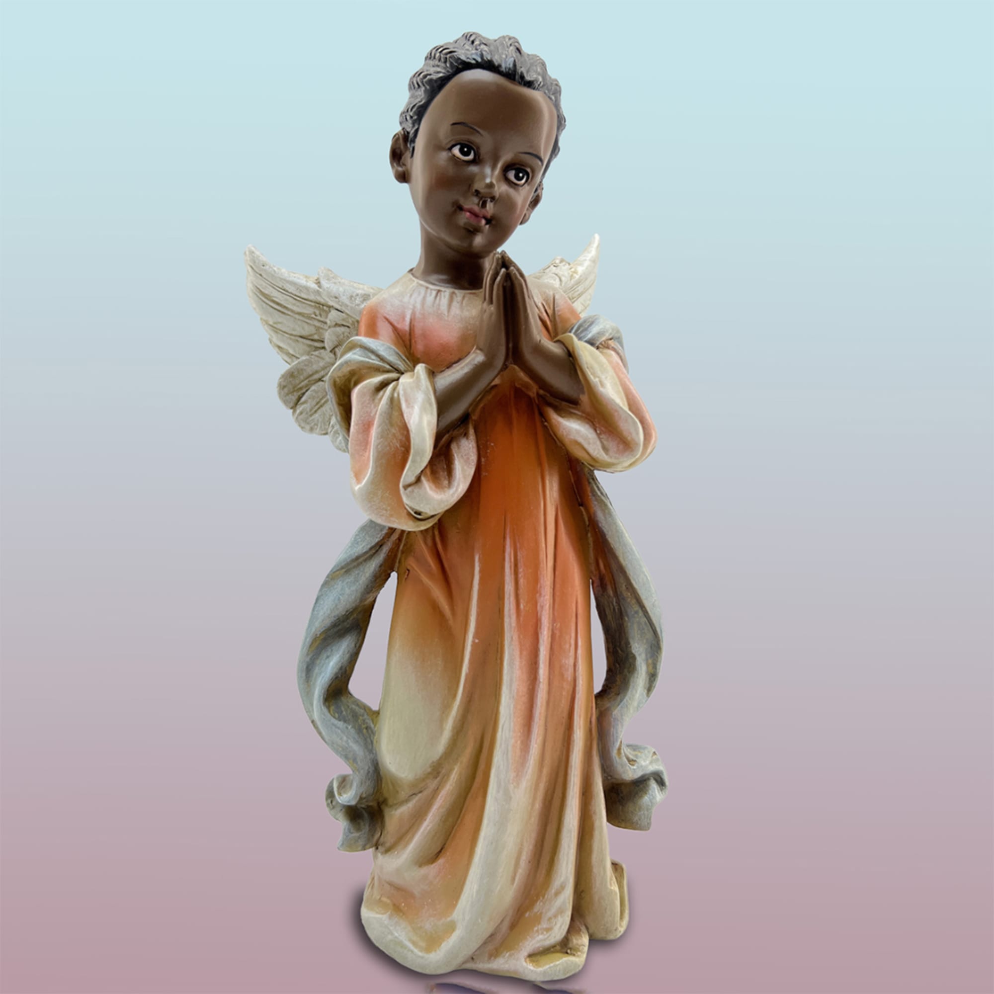 Decorative angel figurine in a peach and cream robe with folded hands
