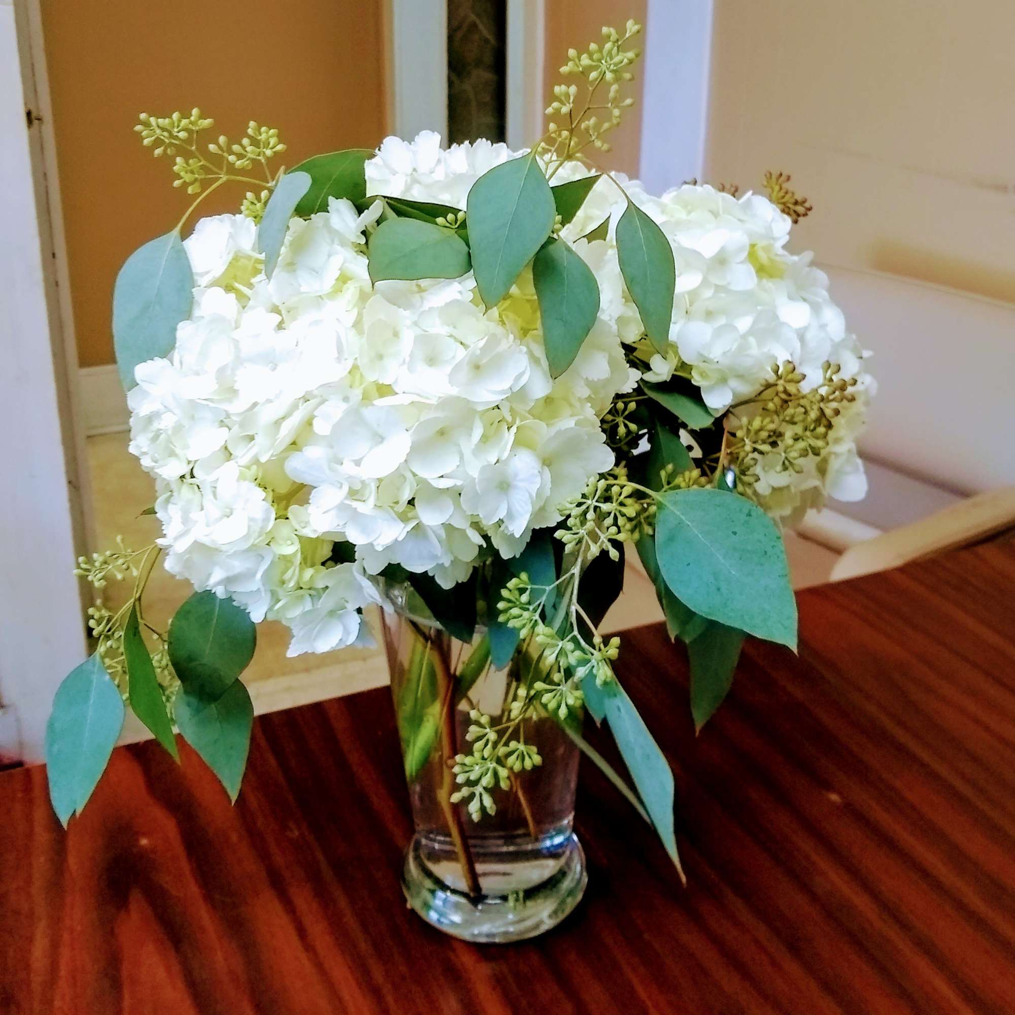 White hydrangea bouquet in a clear glass vase with eucalyptus